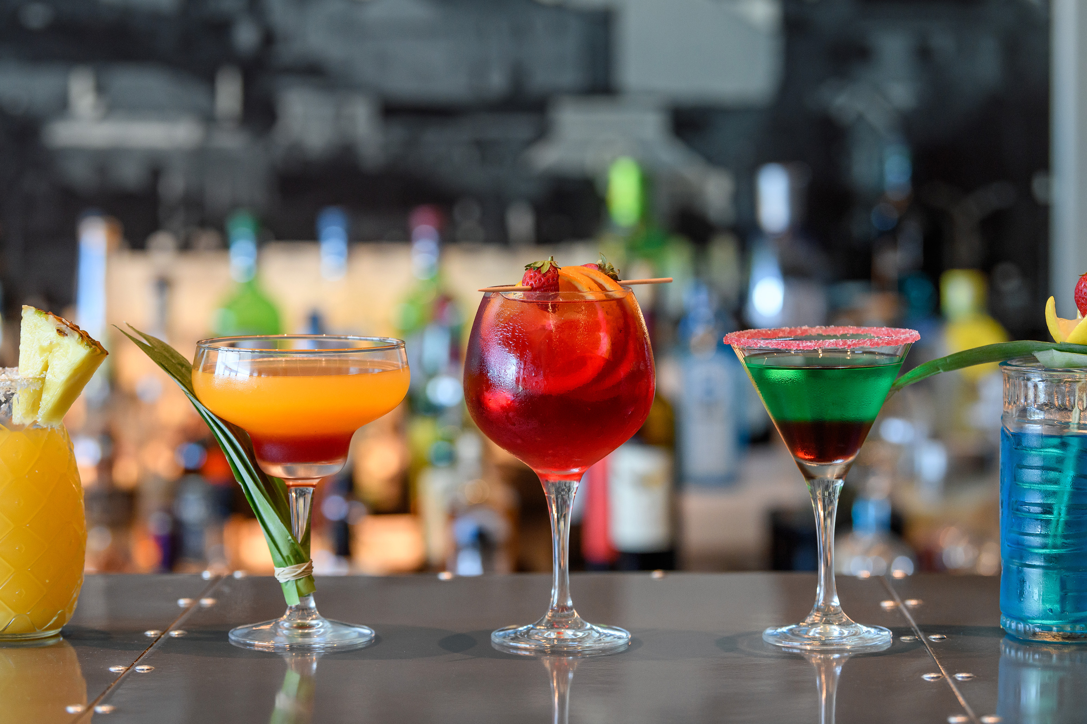 Colorful tropical cocktails and mixed drinks on a bar counter.