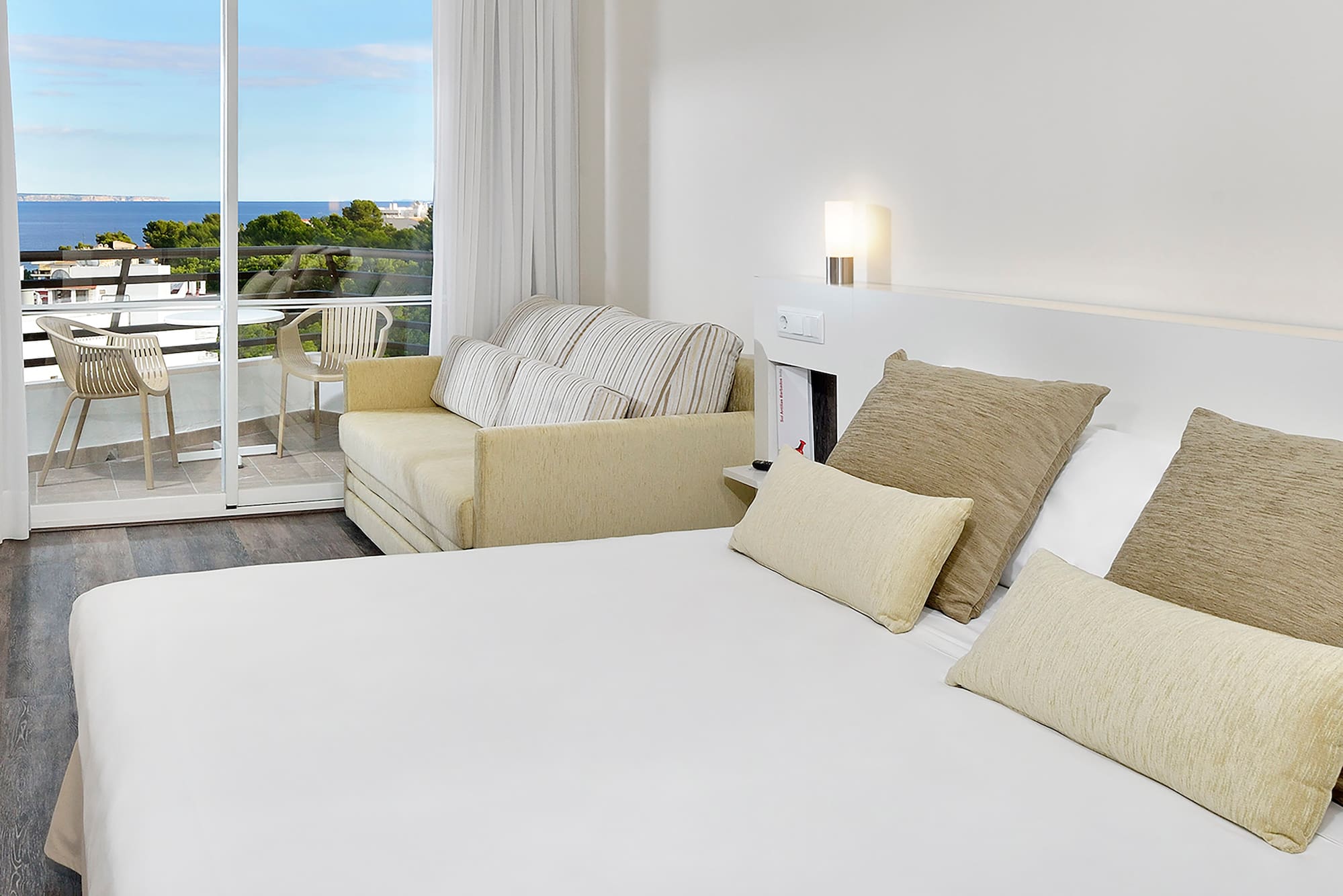 a bed with pillows and a couch in a room with a balcony