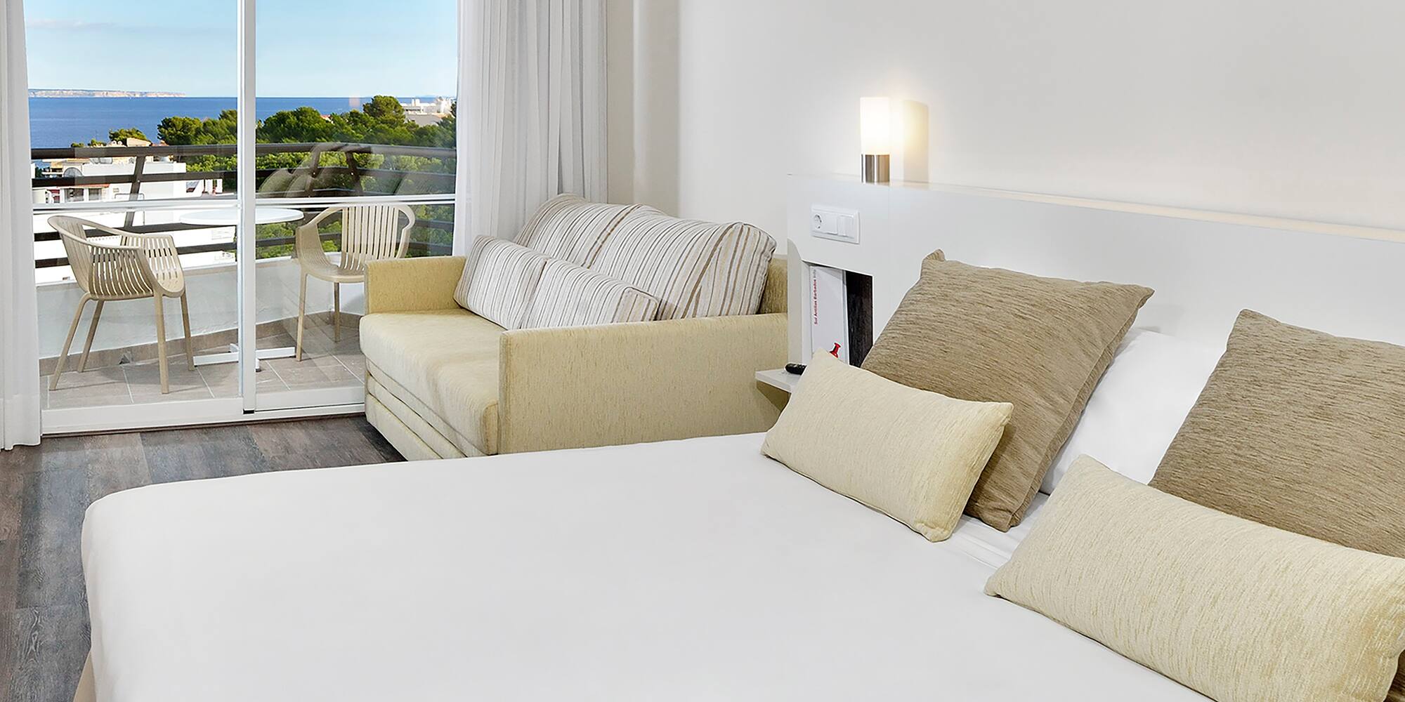 a bed with pillows and a couch in a room with a balcony