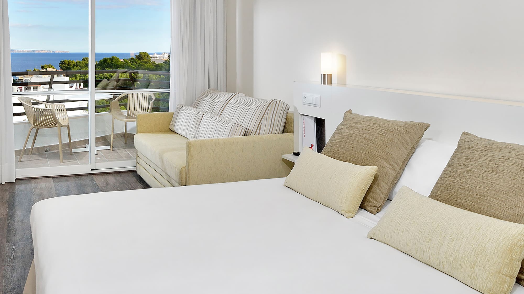 a bed with pillows and a couch in a room with a balcony