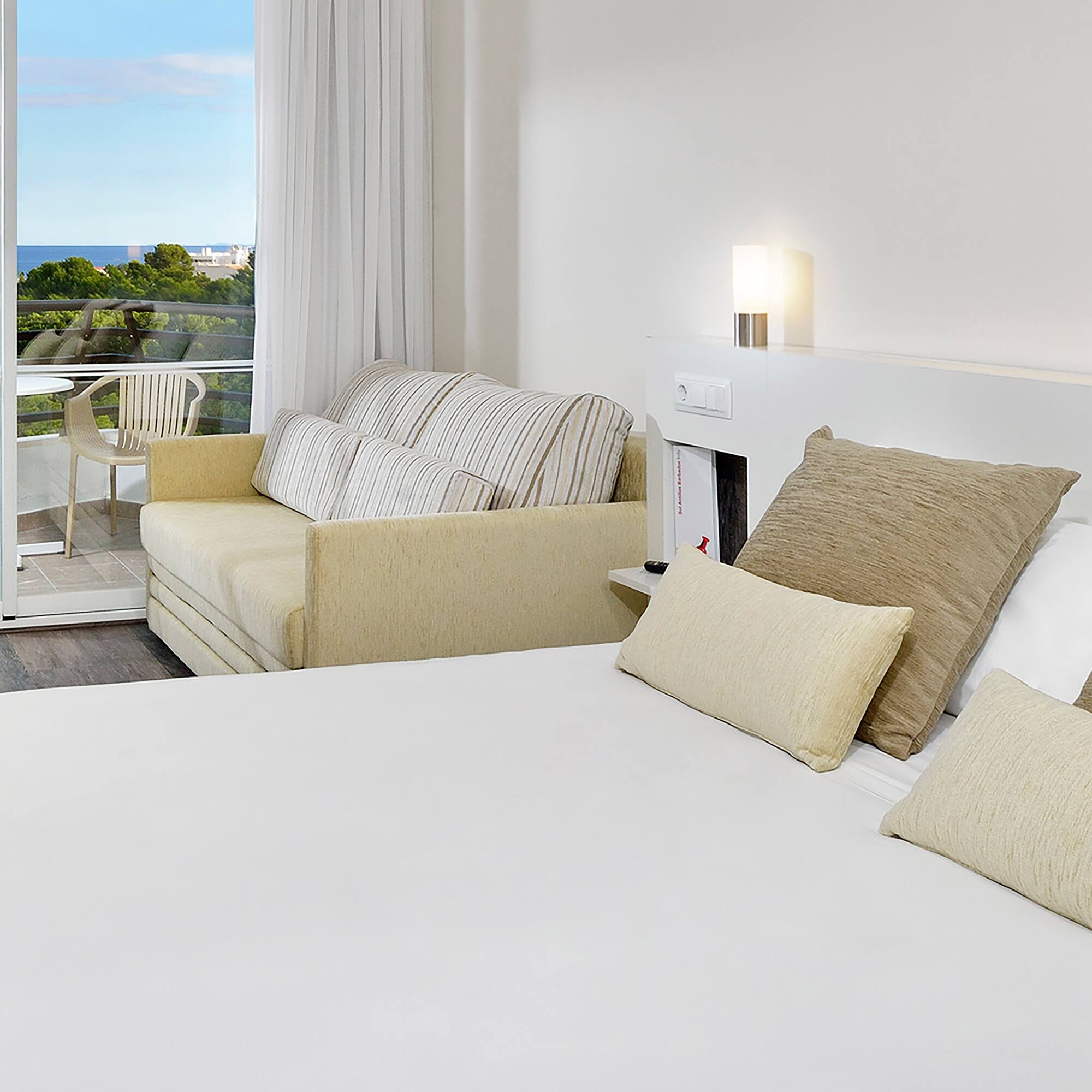 a bed with pillows and a couch in a room with a balcony