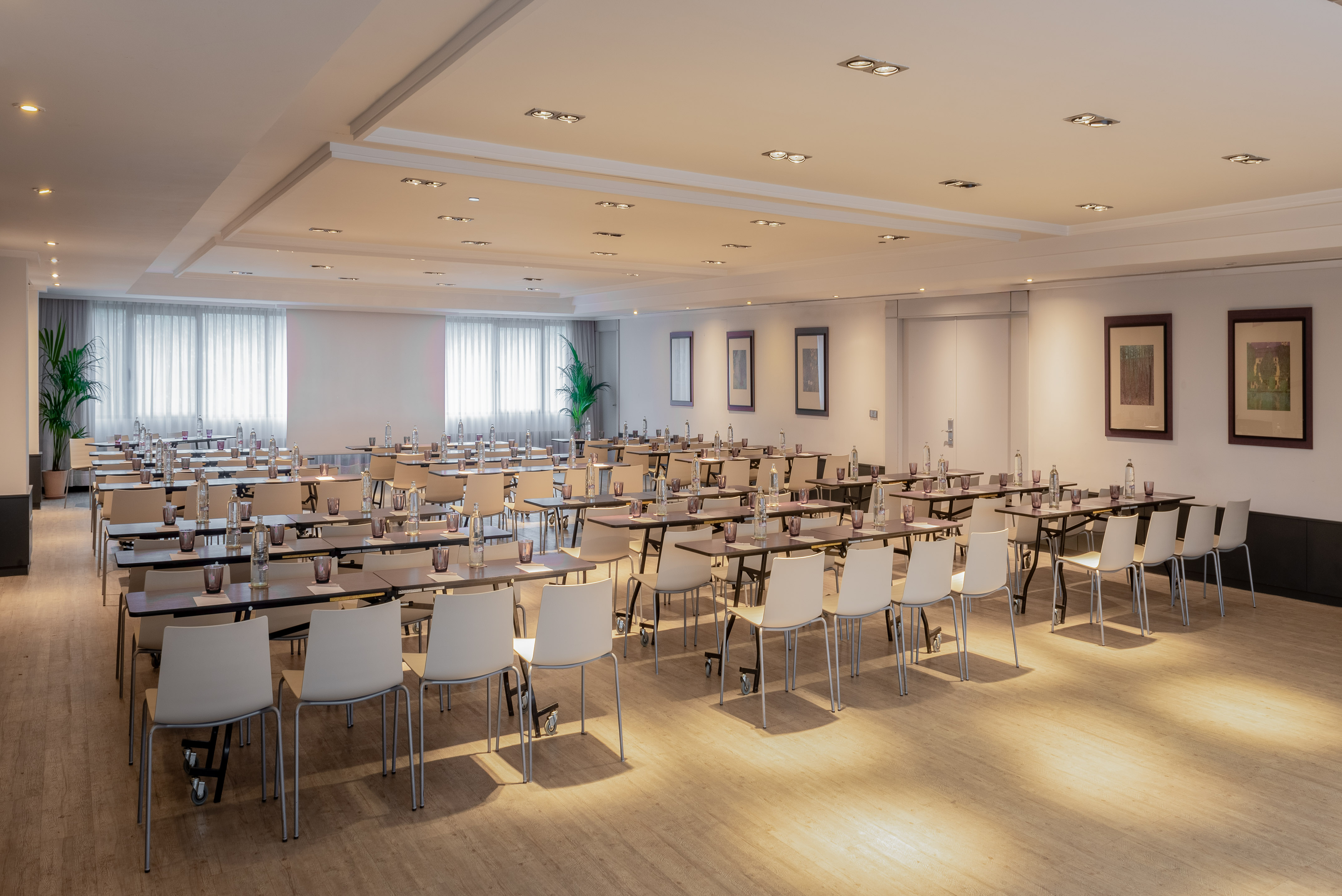 Conference room setup with tables, chairs, water, ready for meetings and seminars.