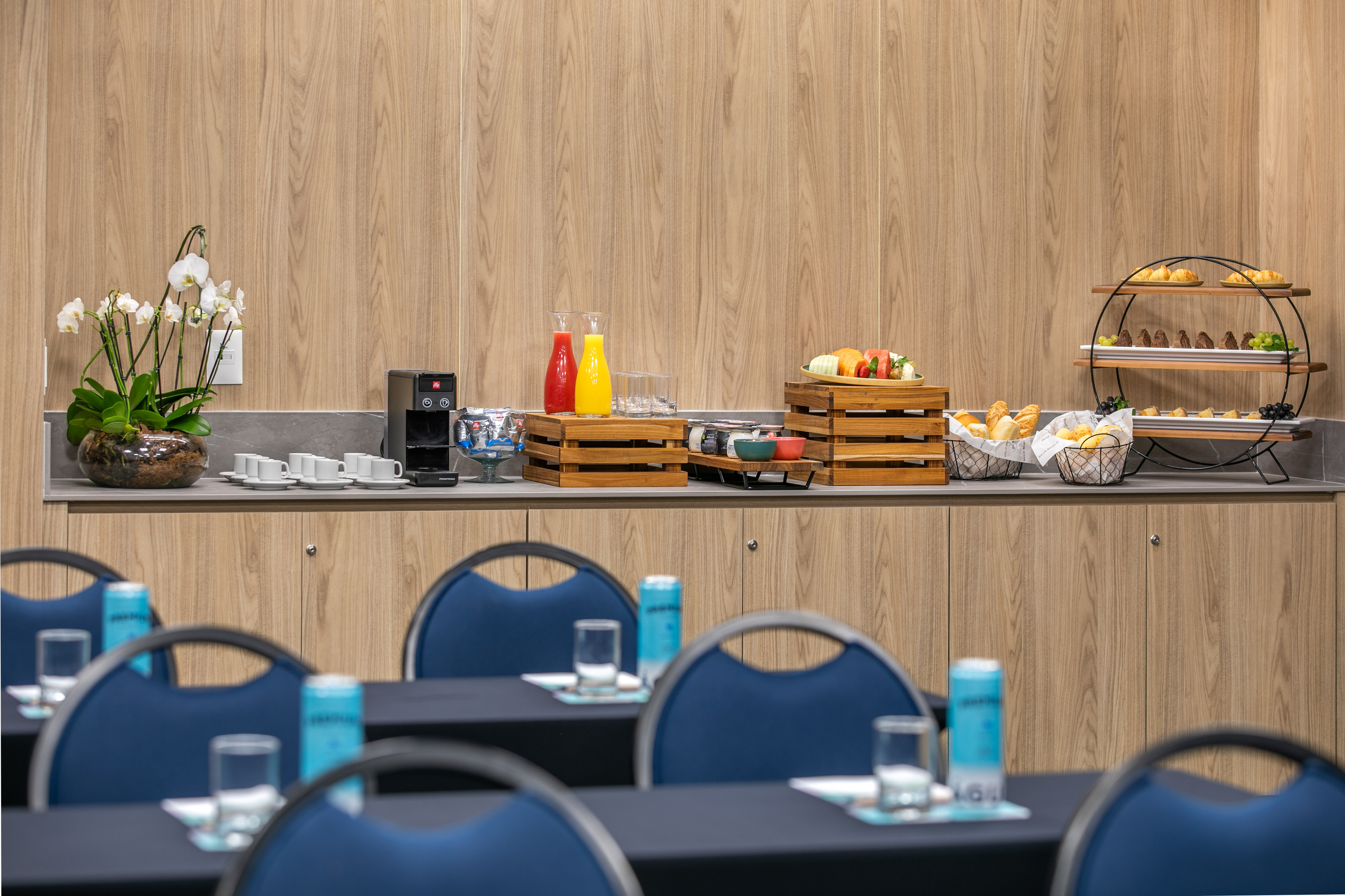Conference coffee break buffet with pastries, fruits, juices, and coffee machine.