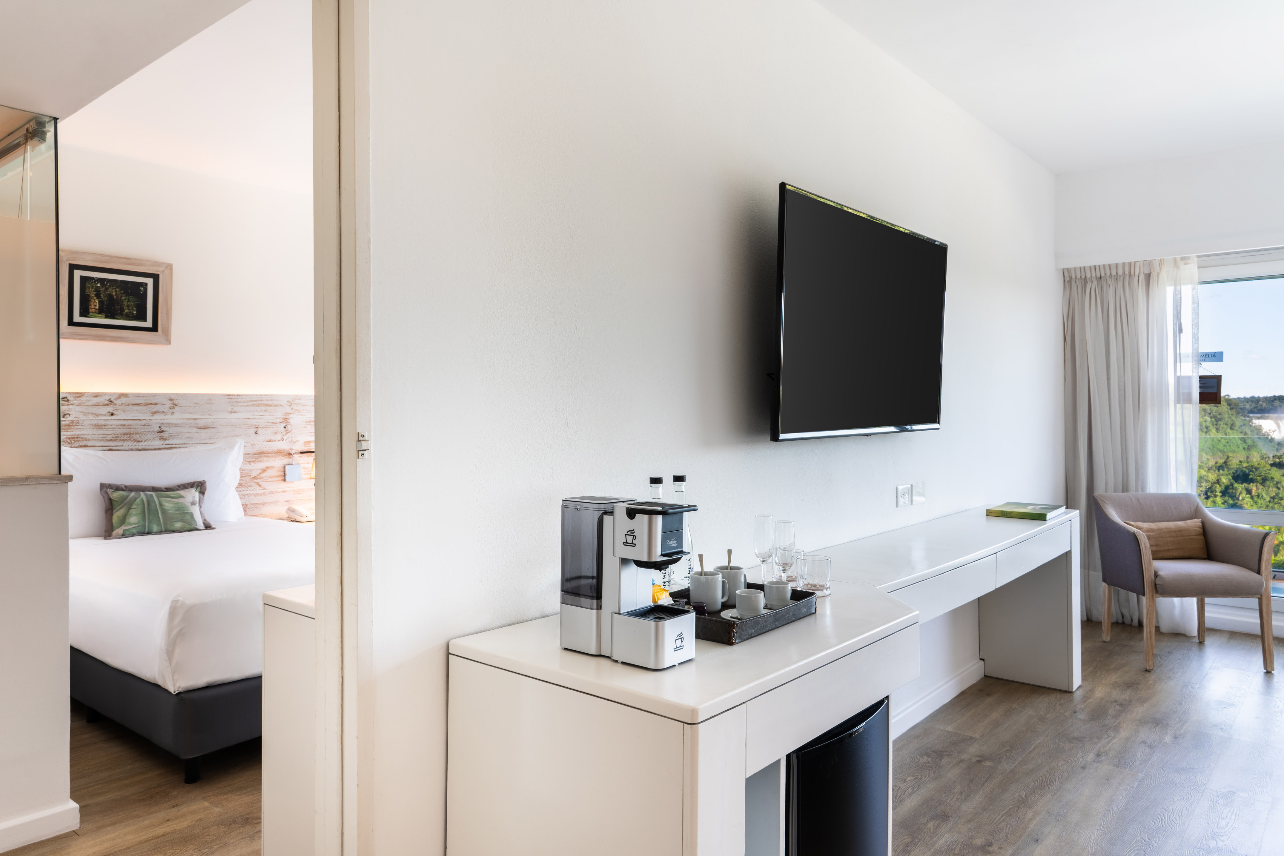 Modern hotel suite with bedroom, TV, coffee maker, and scenic window view. - Family Room - Falls View - Gran Meliá Iguazú, Εθνικό Πάρκο Iguazú