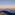 Teide volcano shadow over clouds at sunrise from rocky summit.