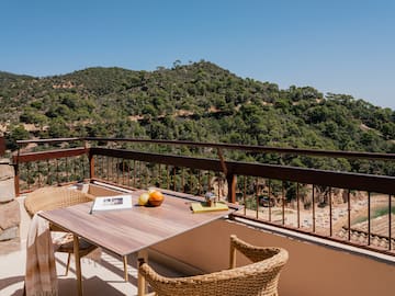 a table and chairs on a balcony overlooking a mountain