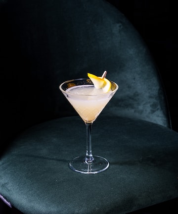 a glass with a drink and a slice of lemon on it