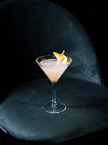 a glass with a drink and a slice of lemon on it