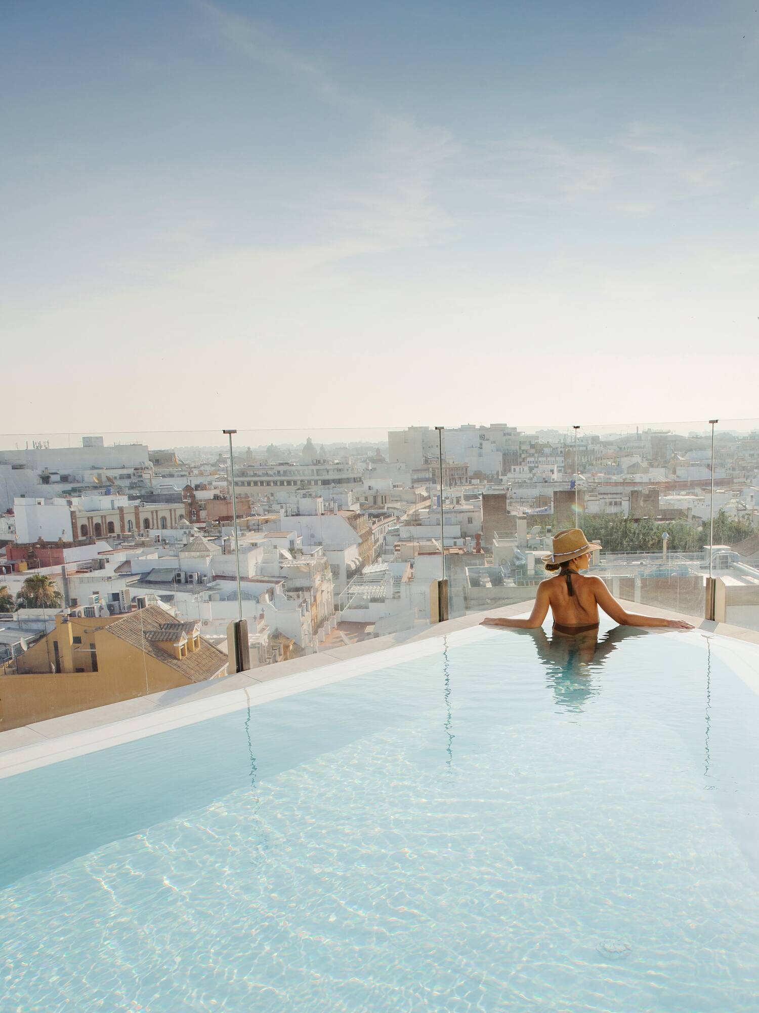 a woman in a swimsuit in a pool overlooking a city