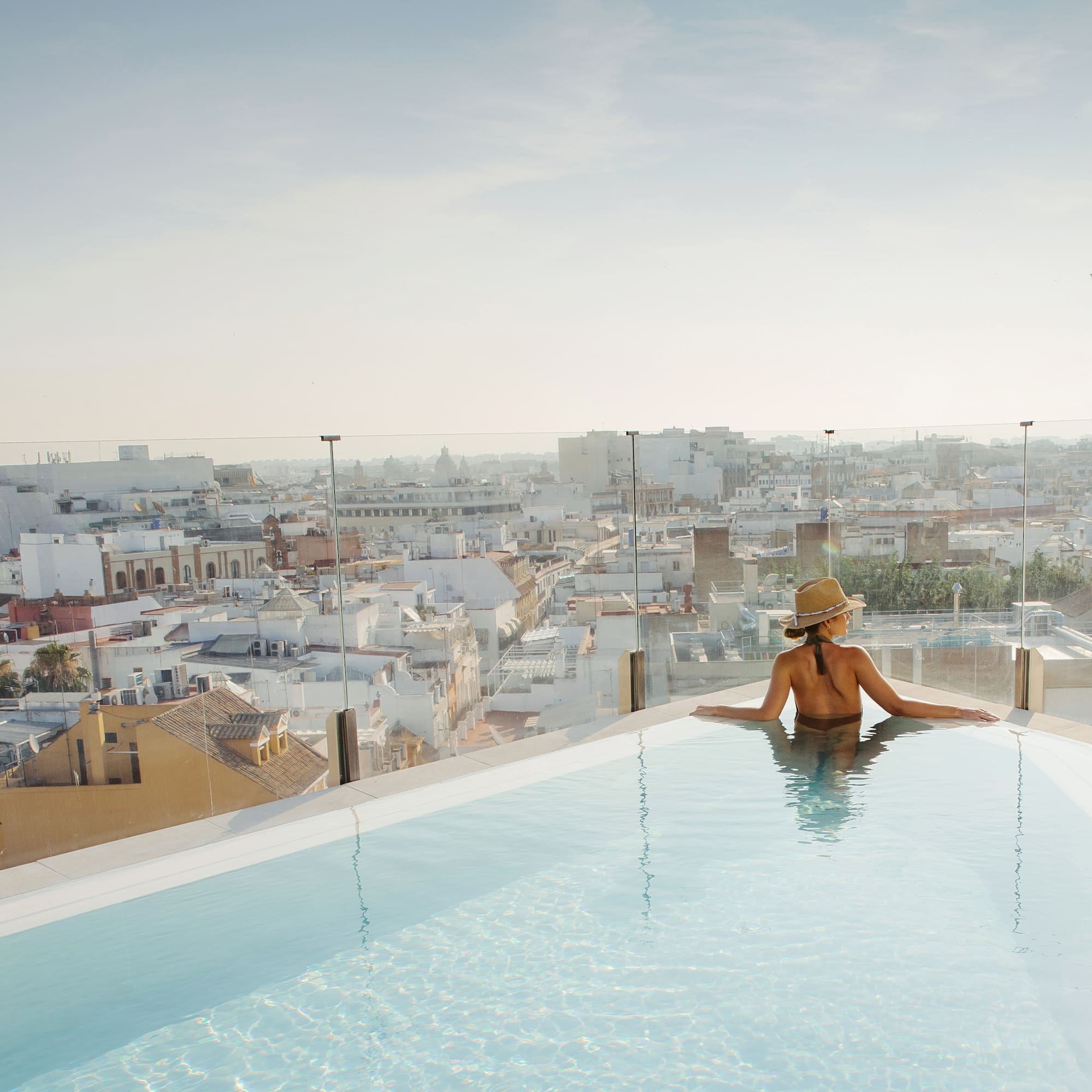 a woman in a swimsuit in a pool overlooking a city
