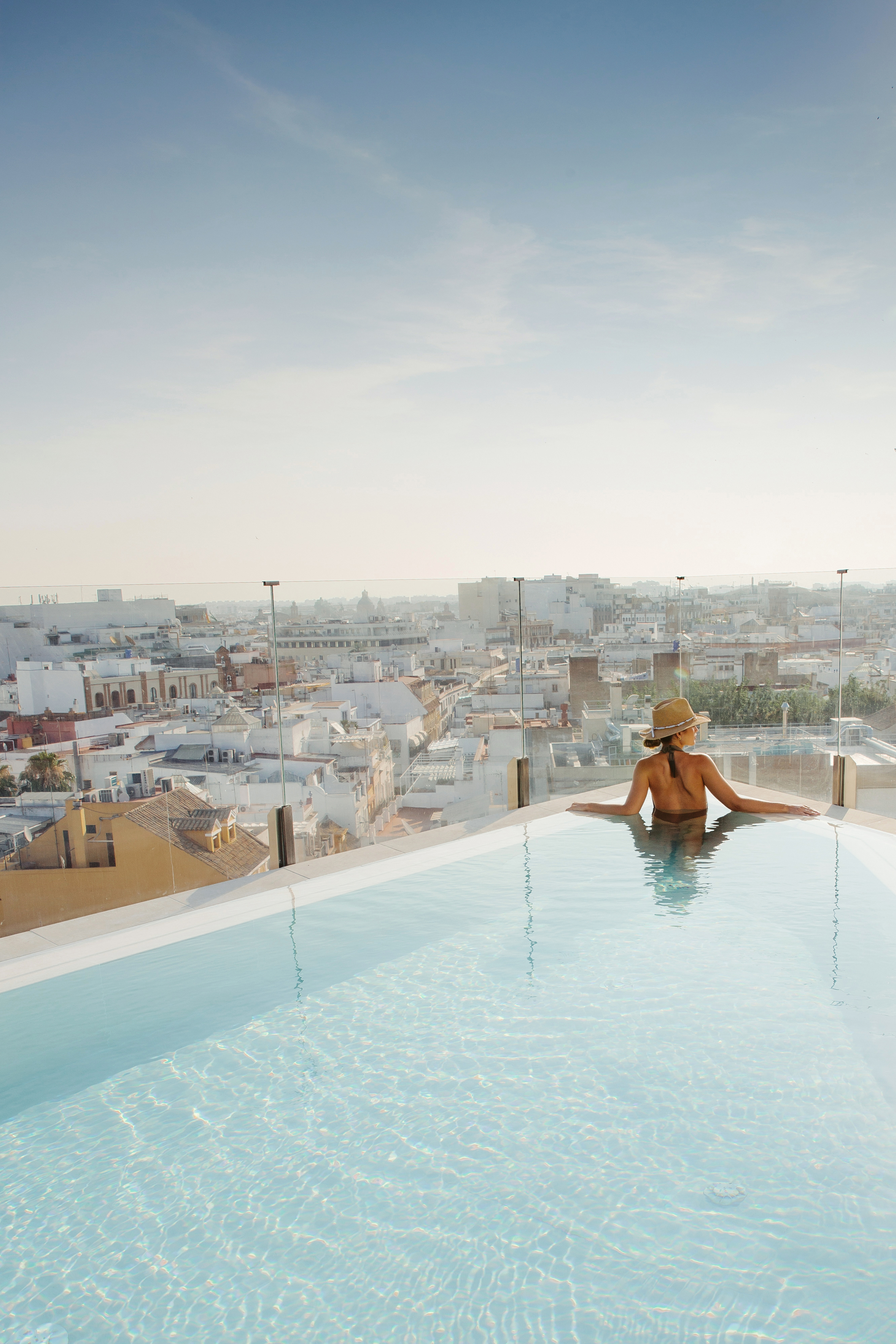a woman in a swimsuit in a pool overlooking a city