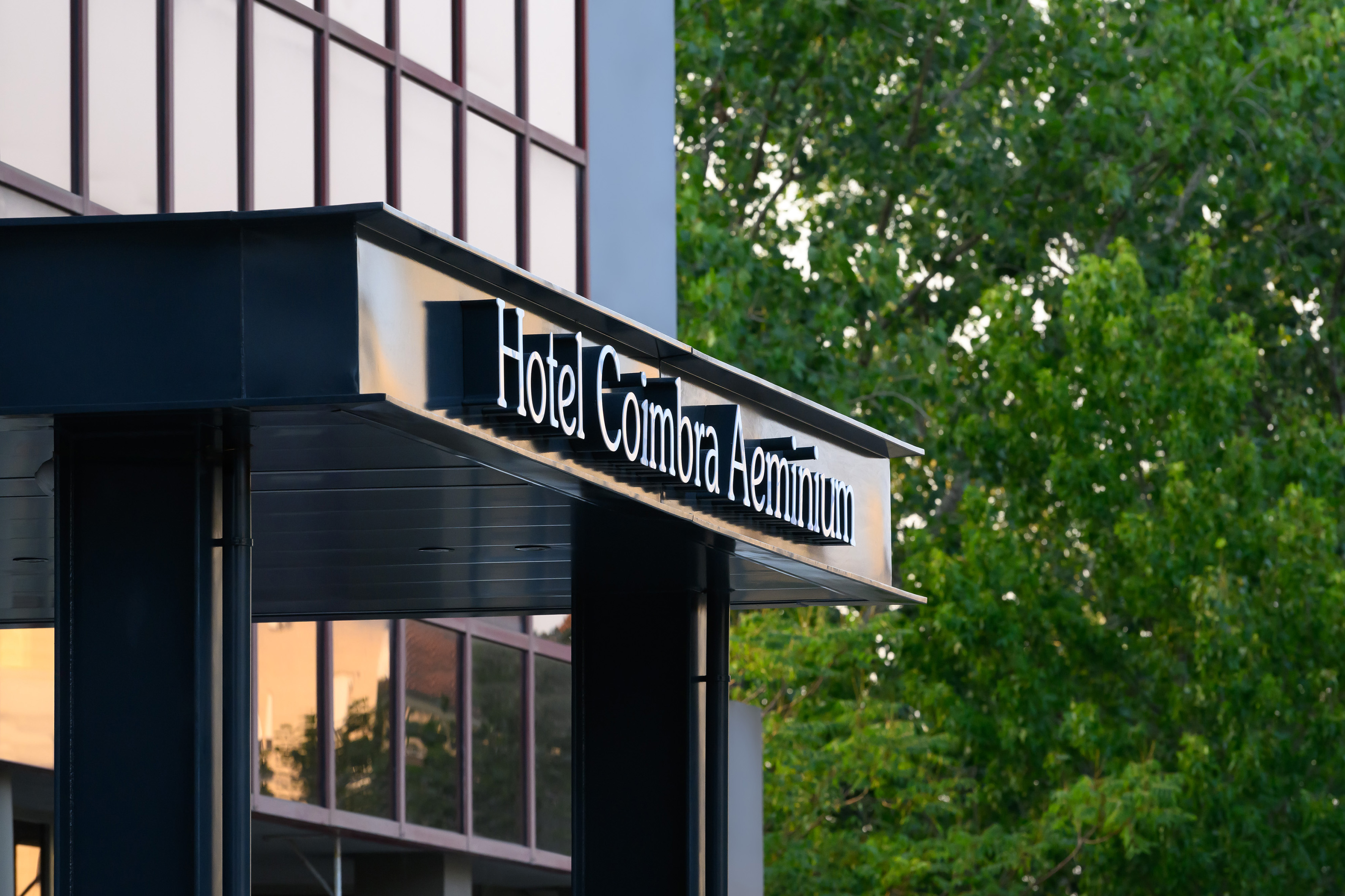 Hotel Coimbra Aeminiun entrance sign, white dimensional letters on dark awning.