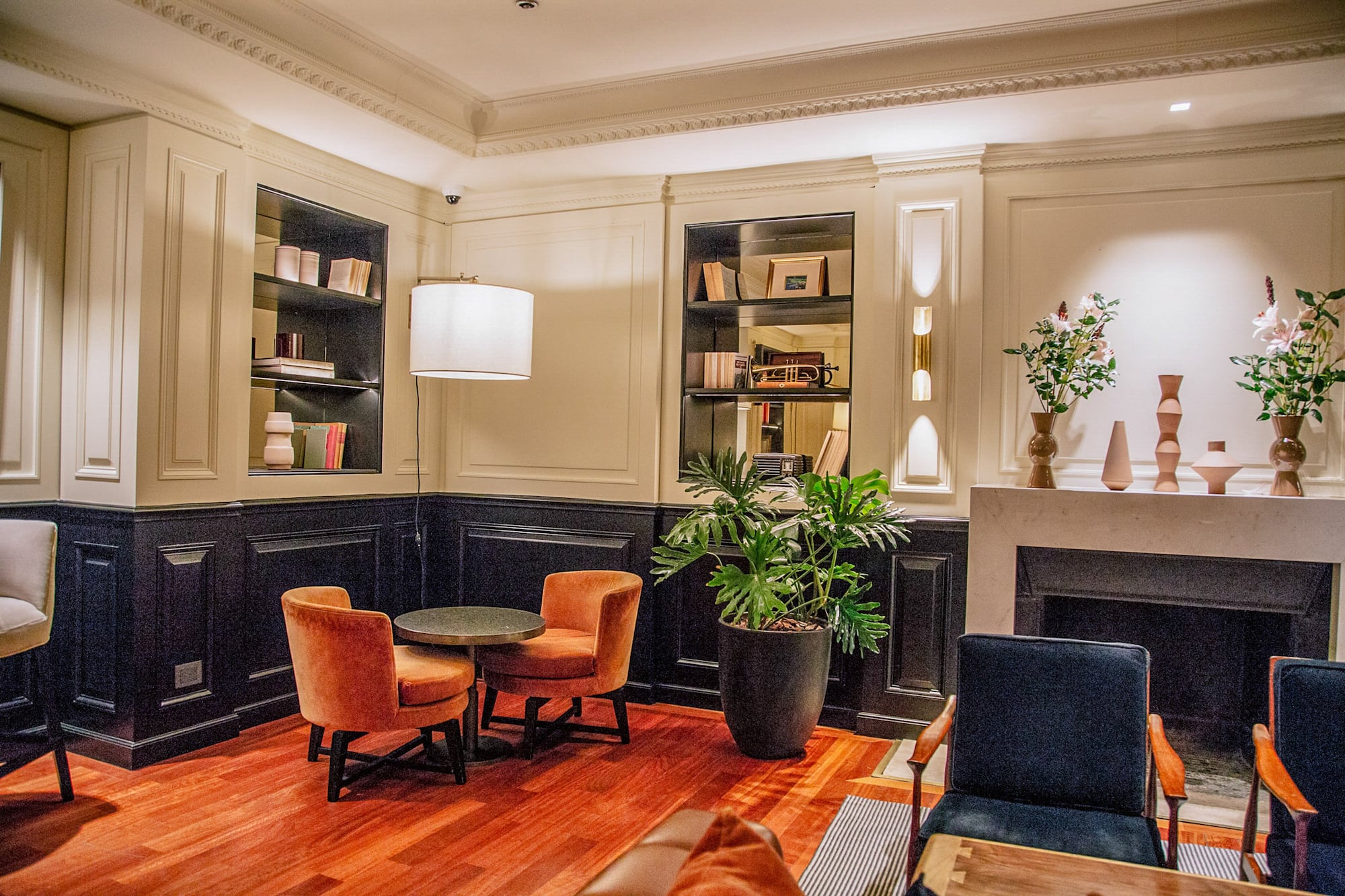 Elegant lounge with orange armchairs, bookshelf, and fireplace.