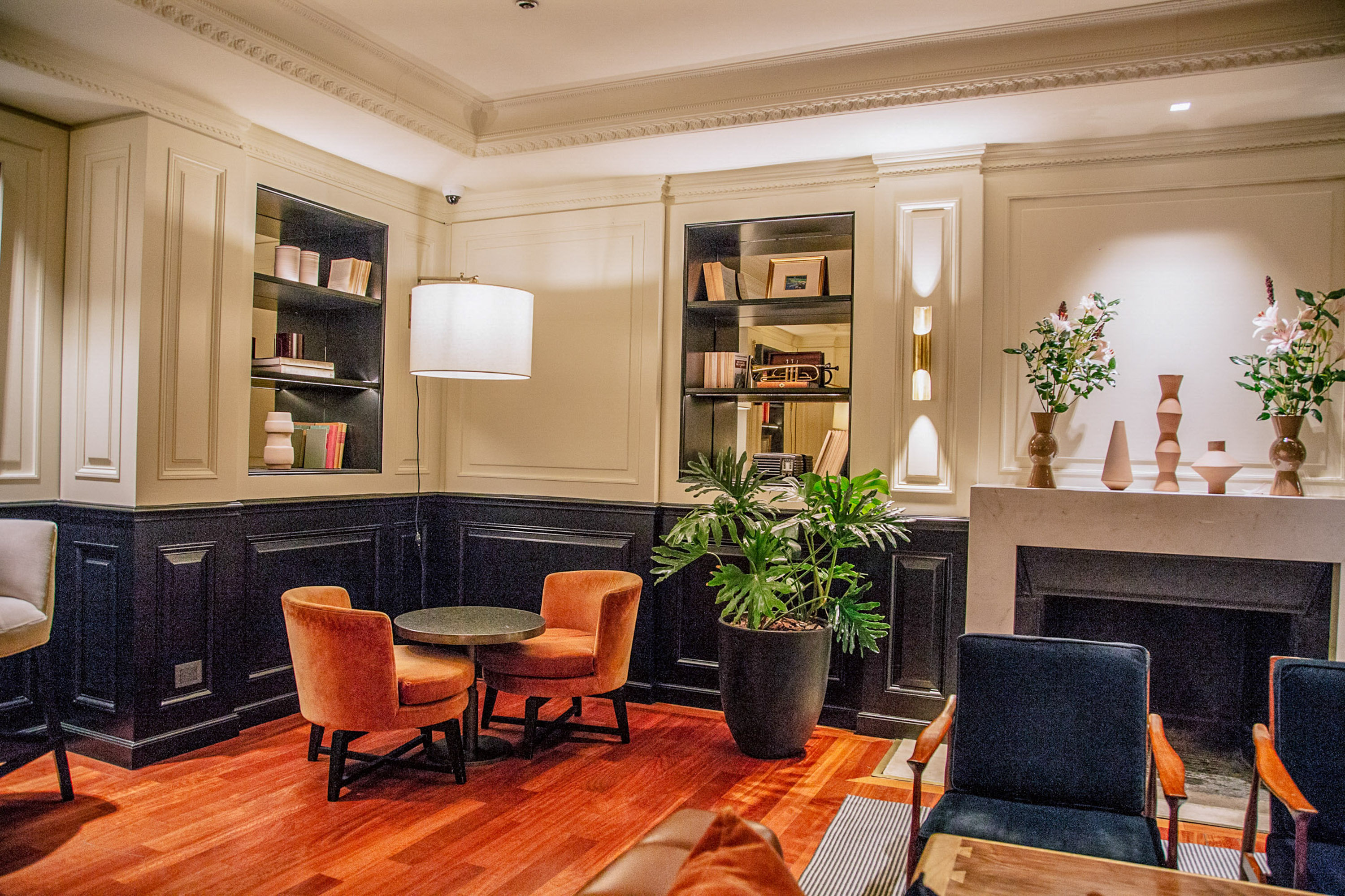 Elegant lounge with orange armchairs, bookshelf, and fireplace.