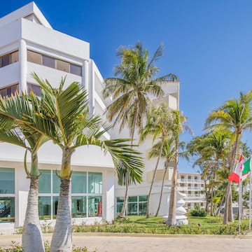 a white building with palm trees and flags