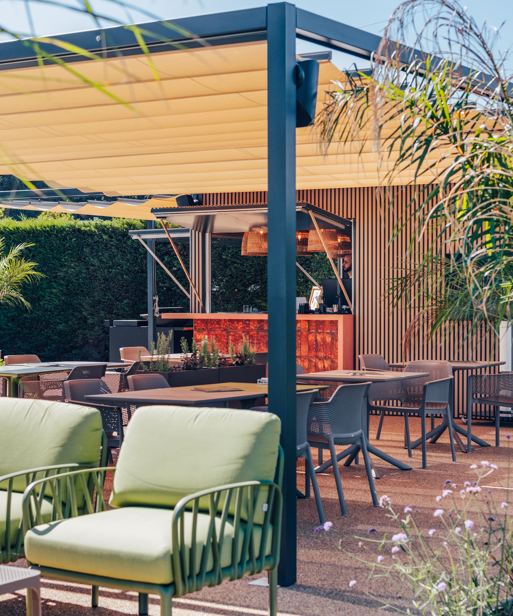 Modern outdoor patio with retractable awning, bar, dining, and lounge areas.