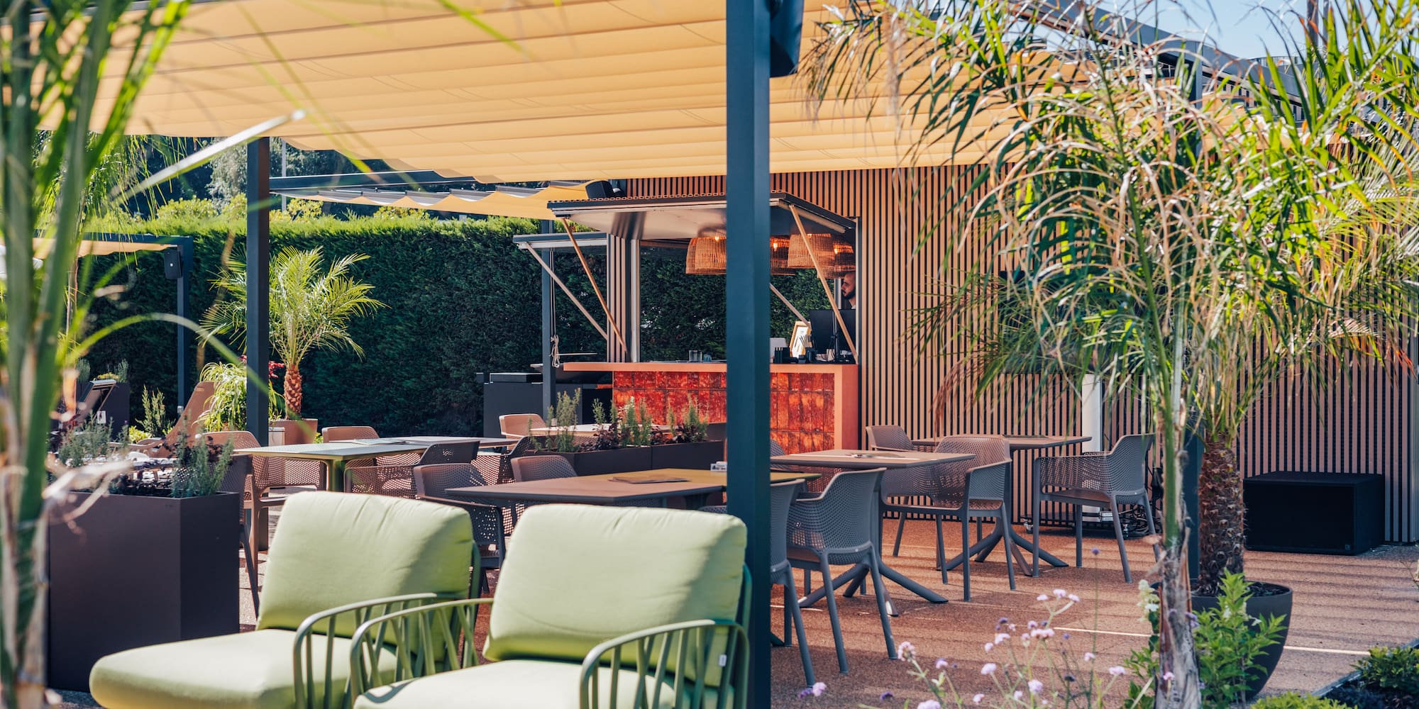 Modern outdoor patio with retractable awning, bar, dining, and lounge areas.