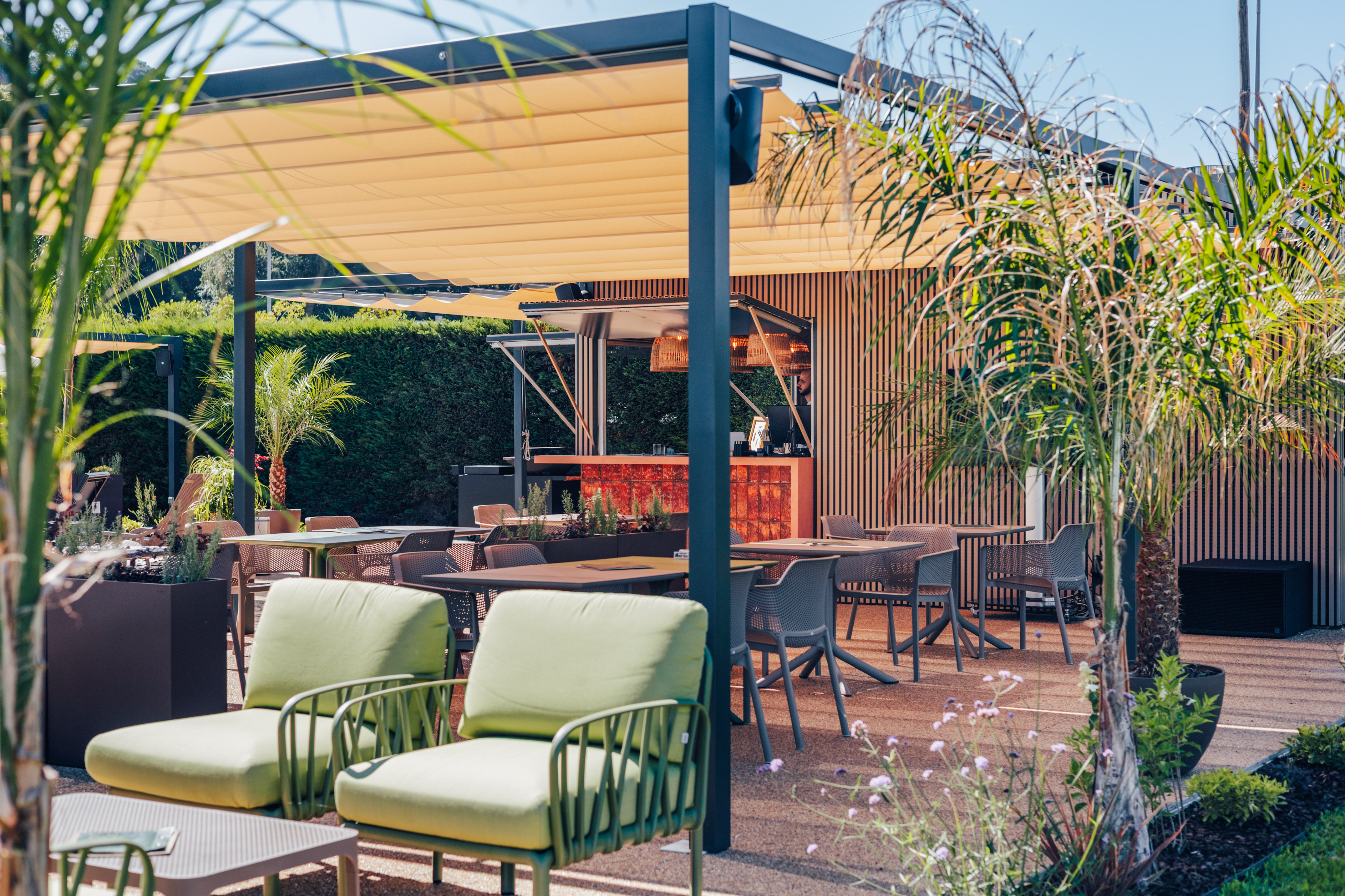 Modern outdoor patio with retractable awning, bar, dining, and lounge areas.