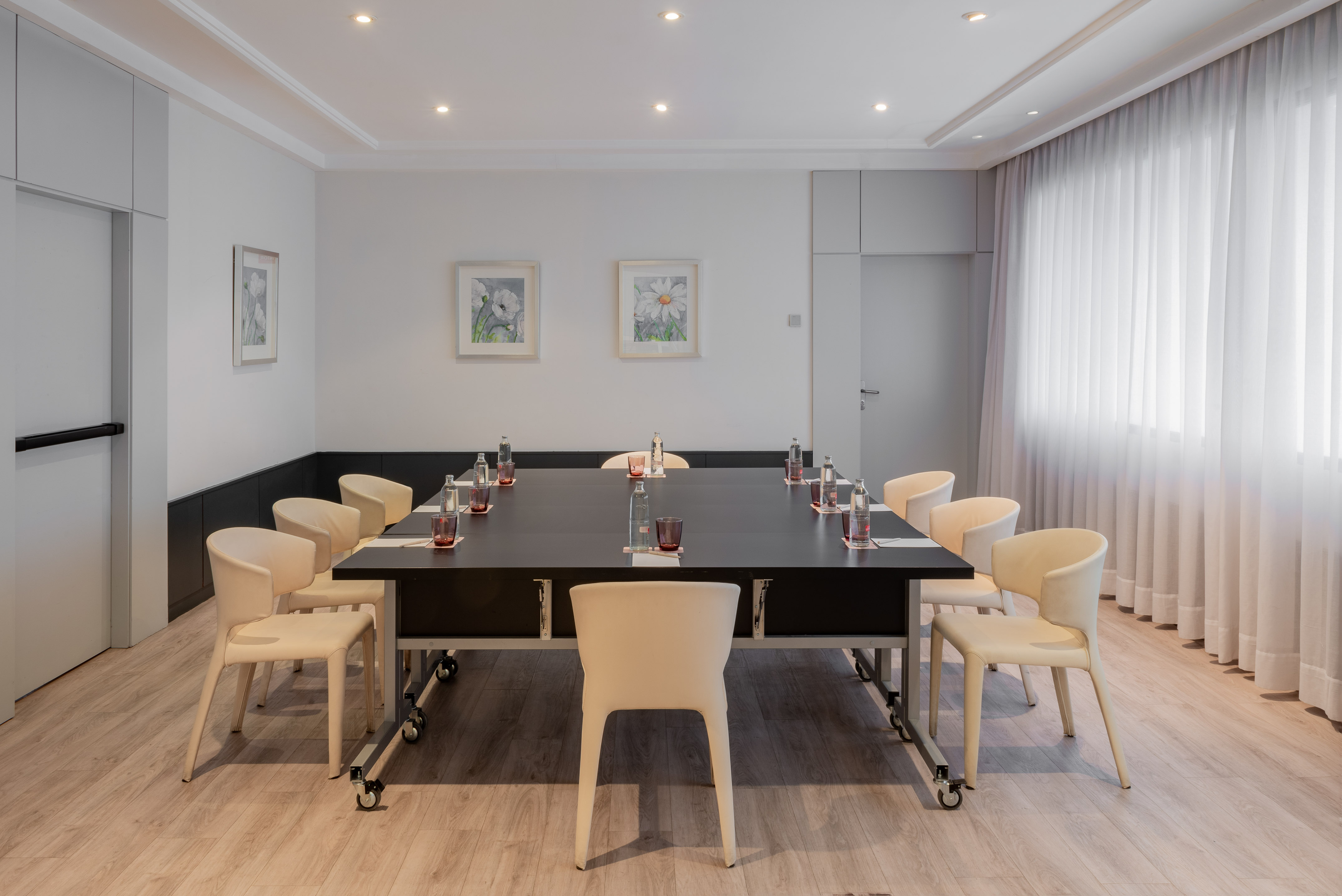 Clean modern meeting room with black table, beige chairs, and wood floor.
