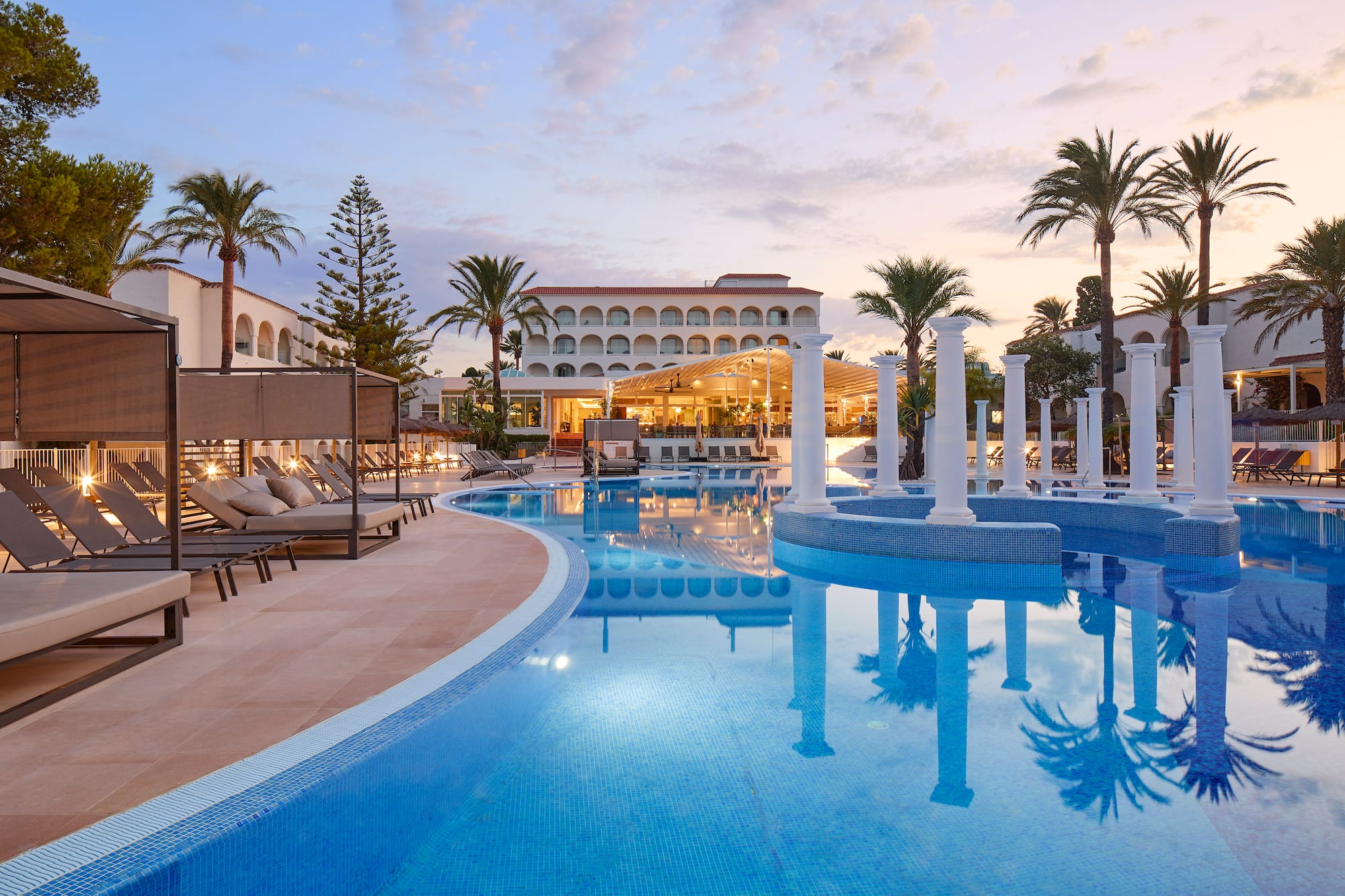 a pool with chairs and a building in the background