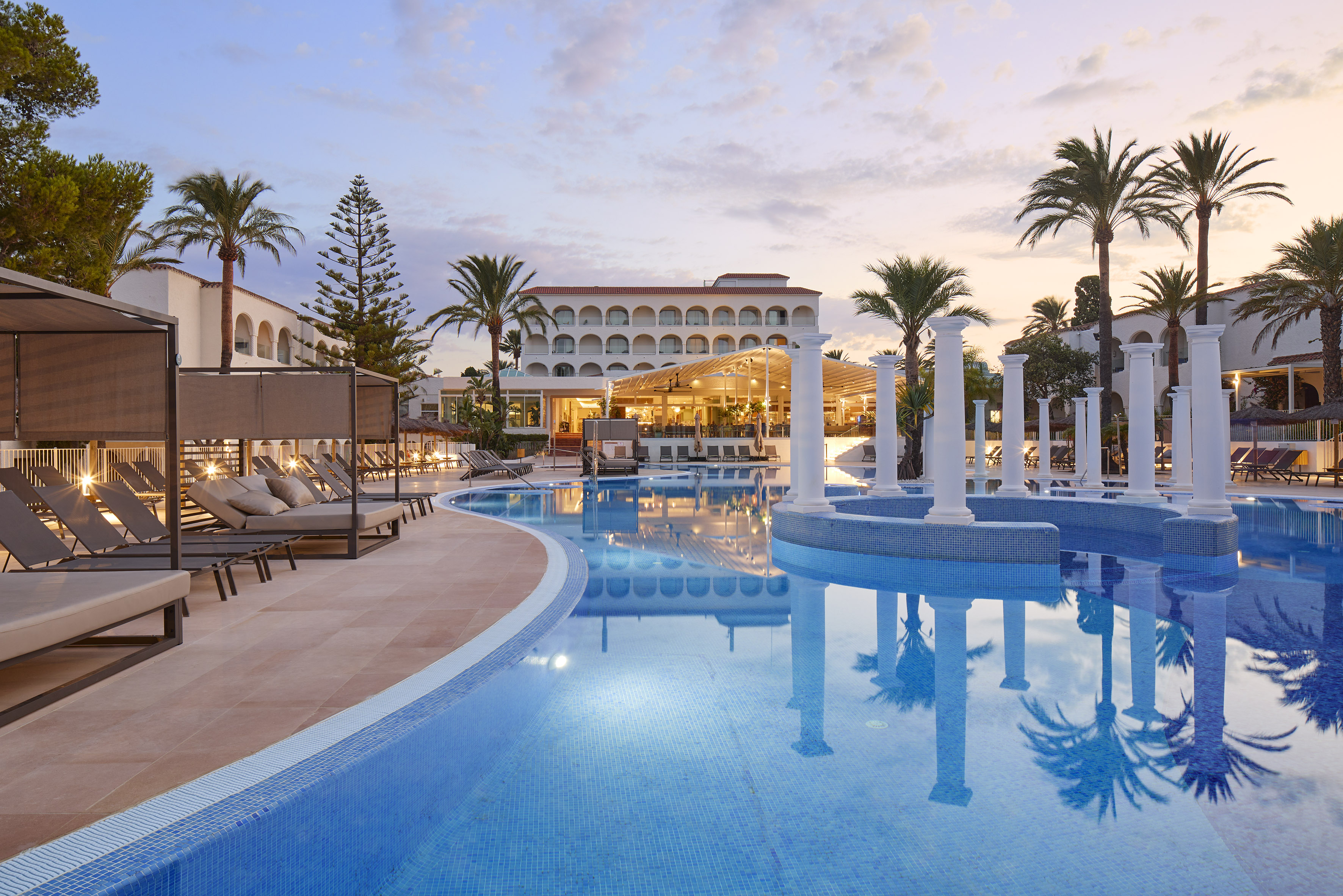 a pool with chairs and a building in the background
