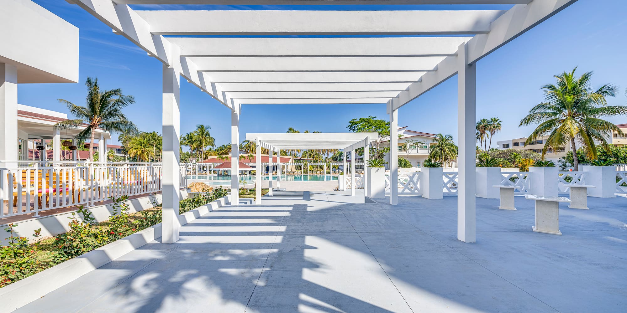 a white structure with pillars and a pool in the background