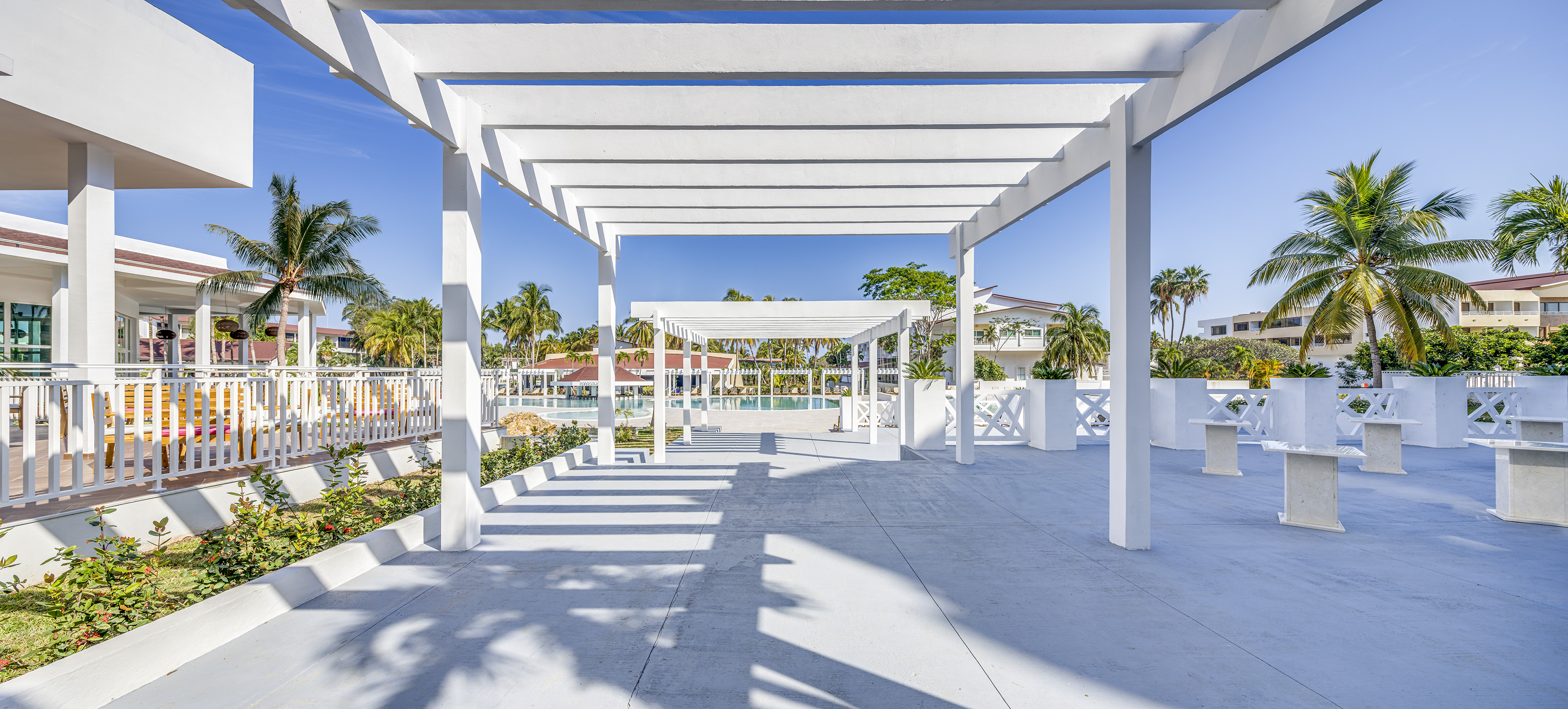 a white structure with pillars and a pool in the background