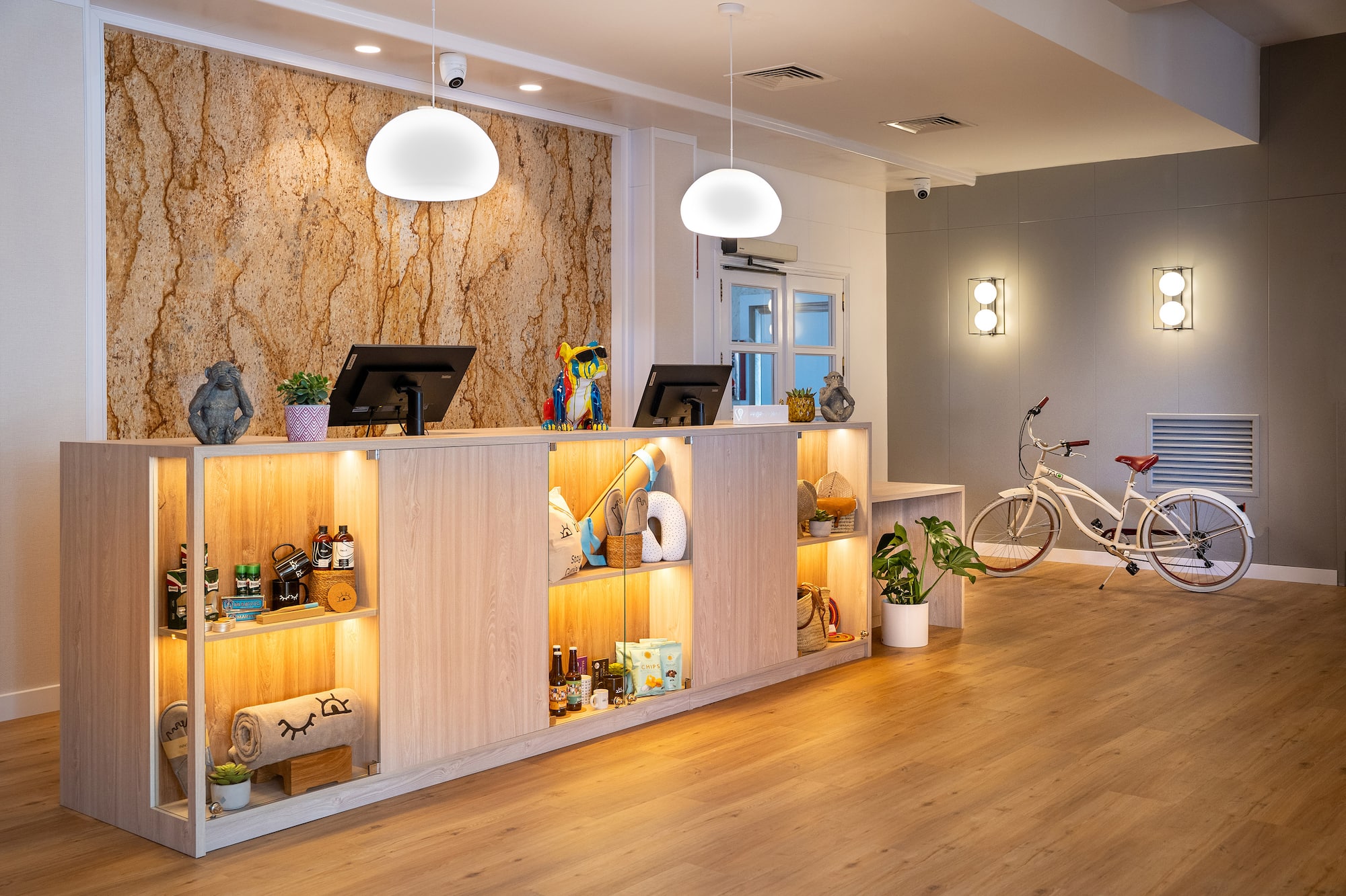 Modern hotel lobby reception with lighted shelves, vintage bicycle, wood floor.