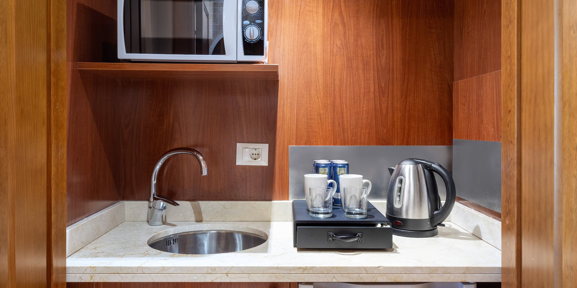 a kitchen with a microwave and coffee cups