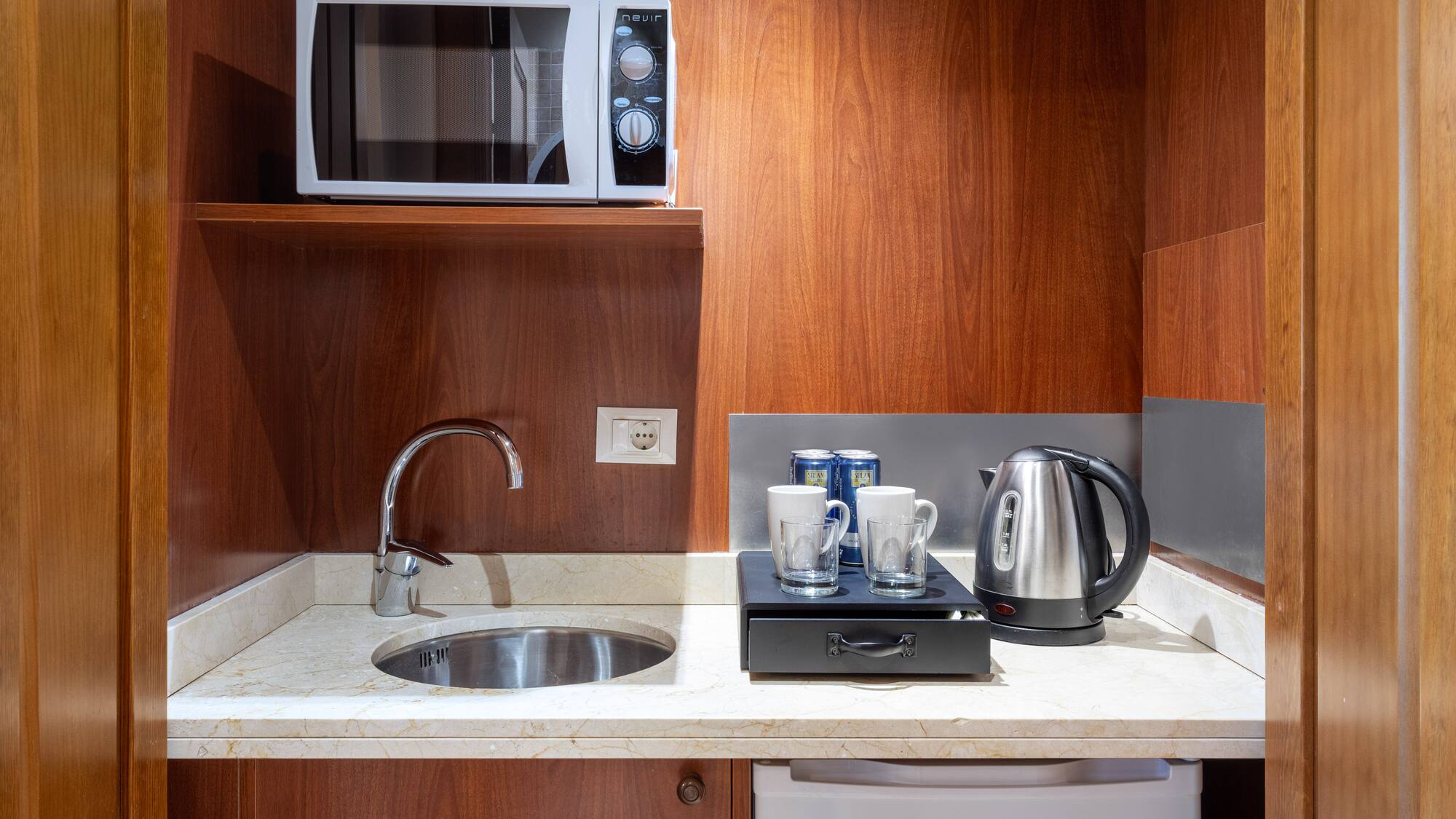 a kitchen with a microwave and coffee cups