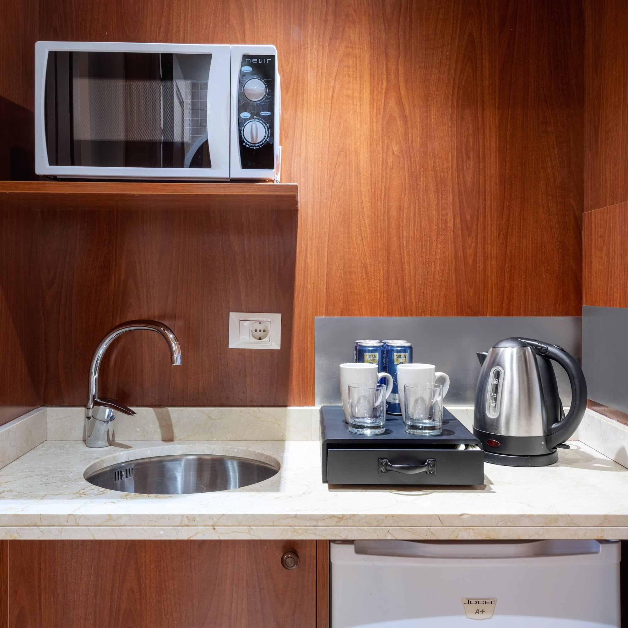 a kitchen with a microwave and coffee cups
