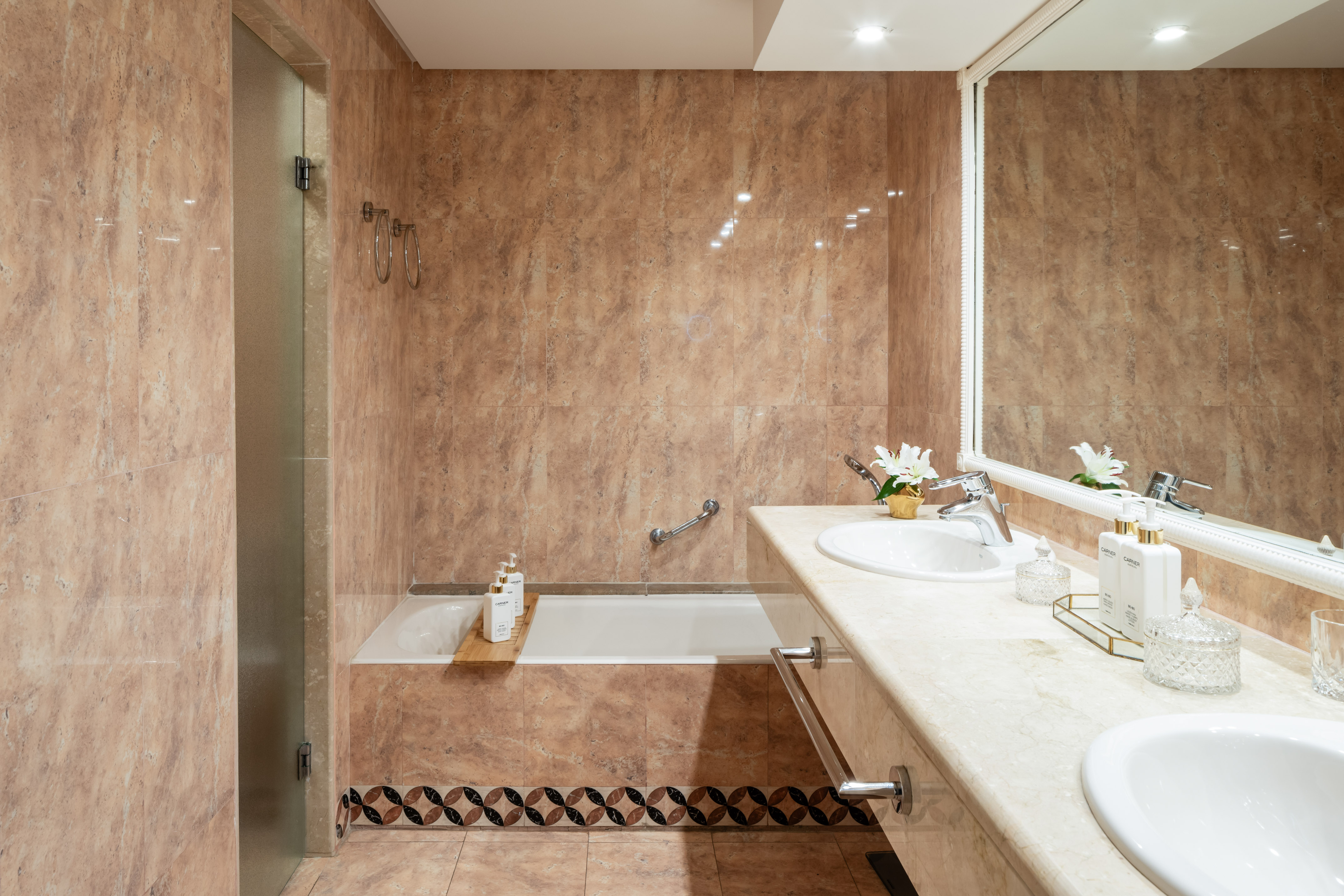 Luxury marble bathroom with double vanity, two sinks, and tub shower.