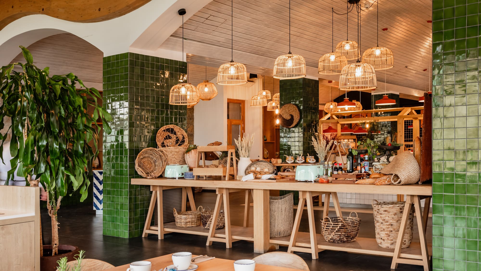 Stylish restaurant interior with buffet, wicker lights, green tiles, and wooden tables.