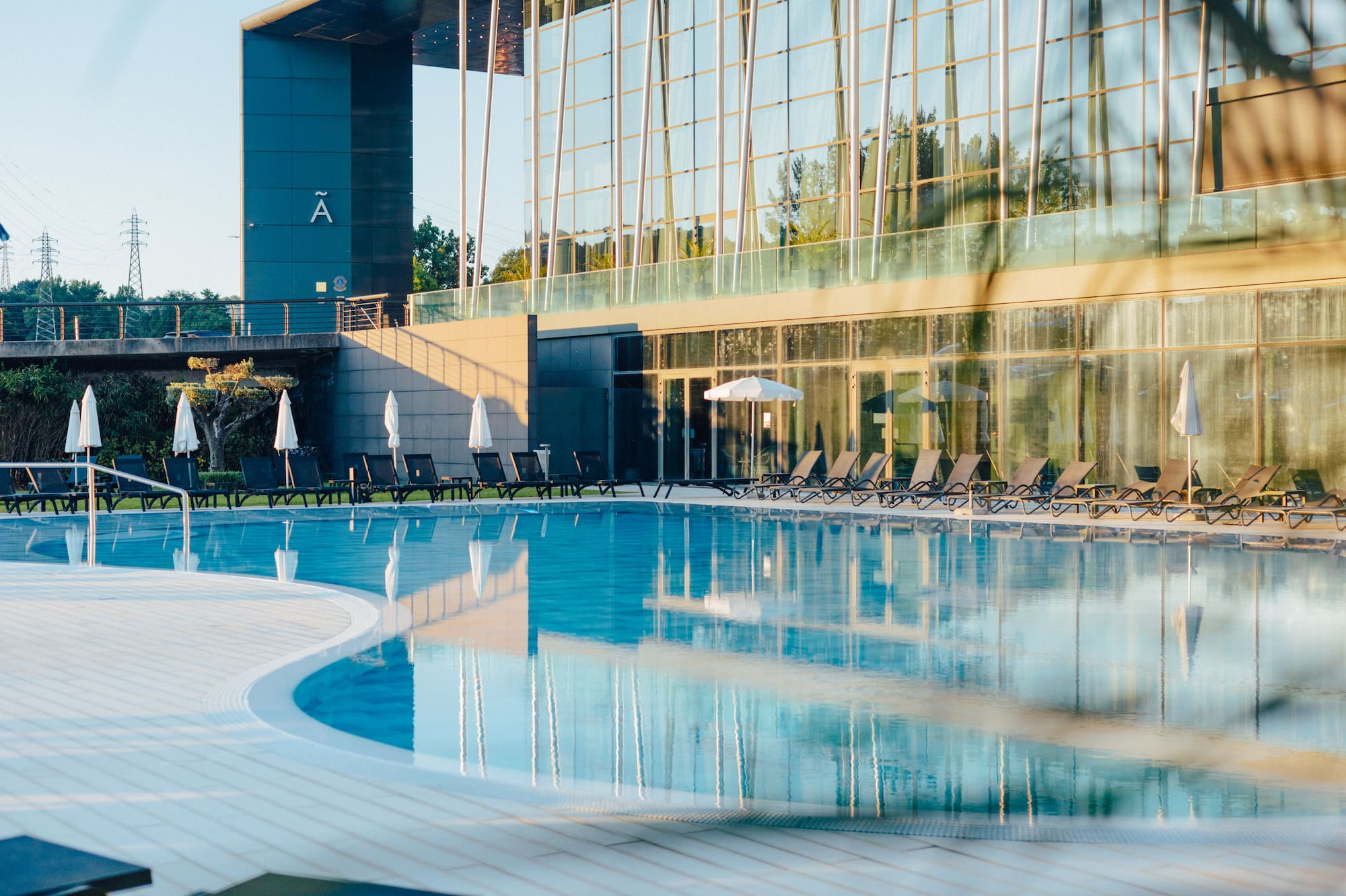 Modern hotel outdoor pool with sun loungers and glass building.