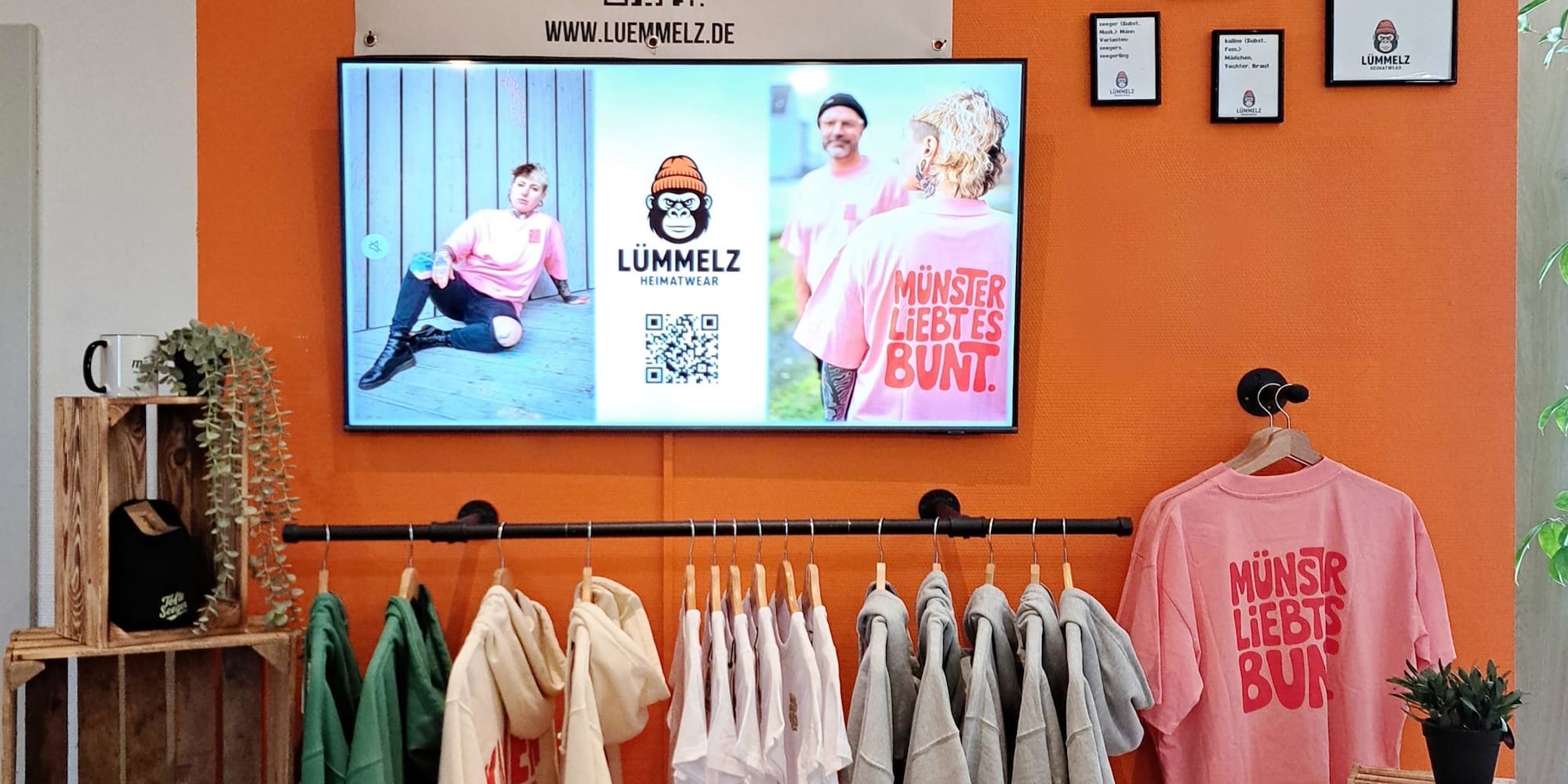 a room with a tv and clothes on the wall