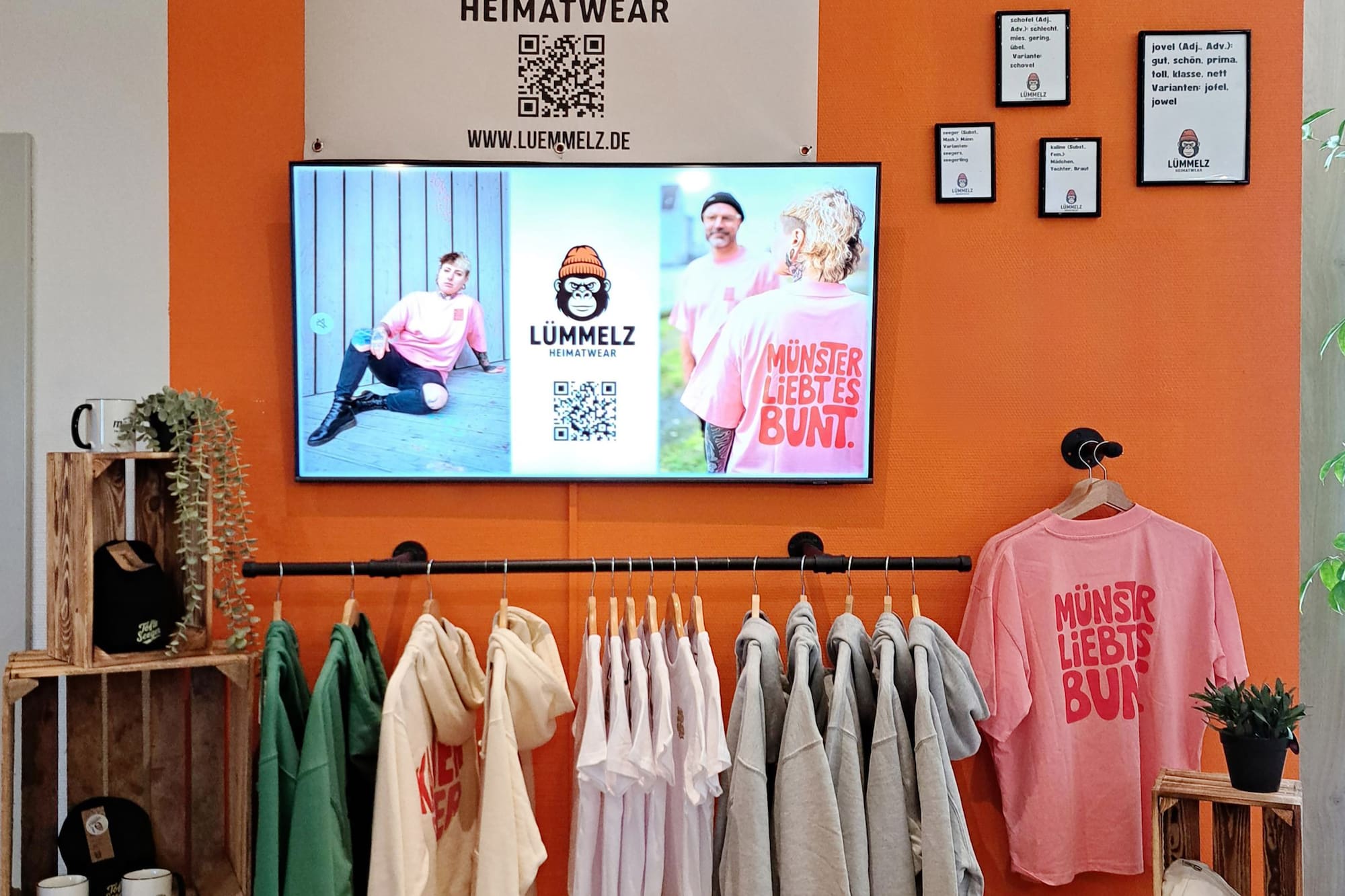 a room with a tv and clothes on the wall