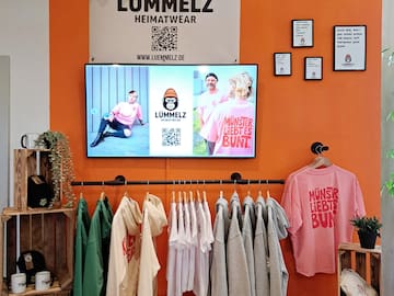 a room with a tv and clothes on the wall