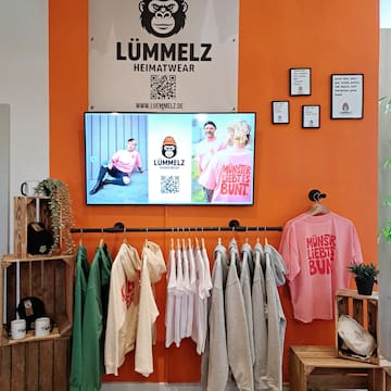 a room with a tv and clothes on the wall