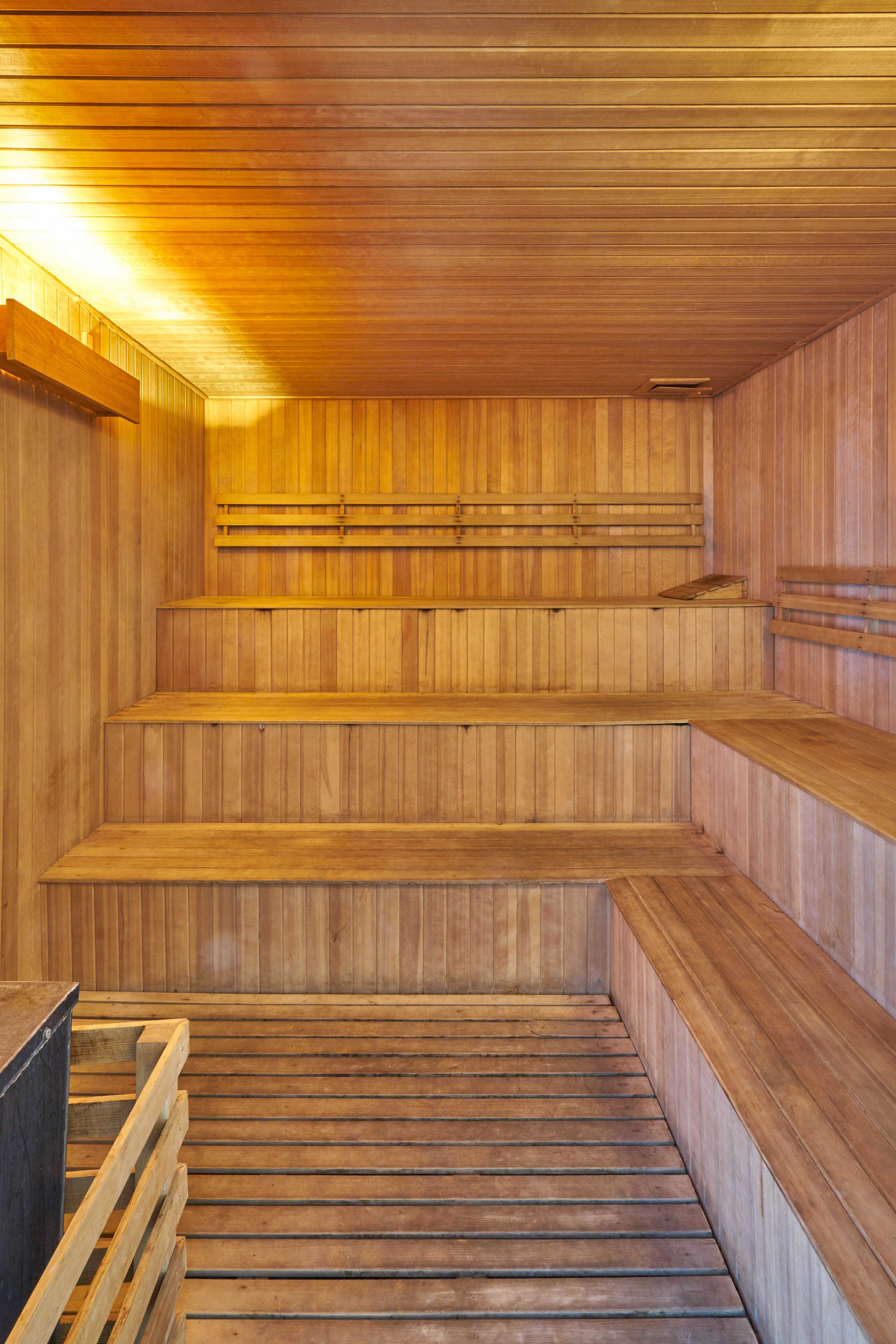 Empty wooden sauna room with tiered benches and warm overhead lighting.