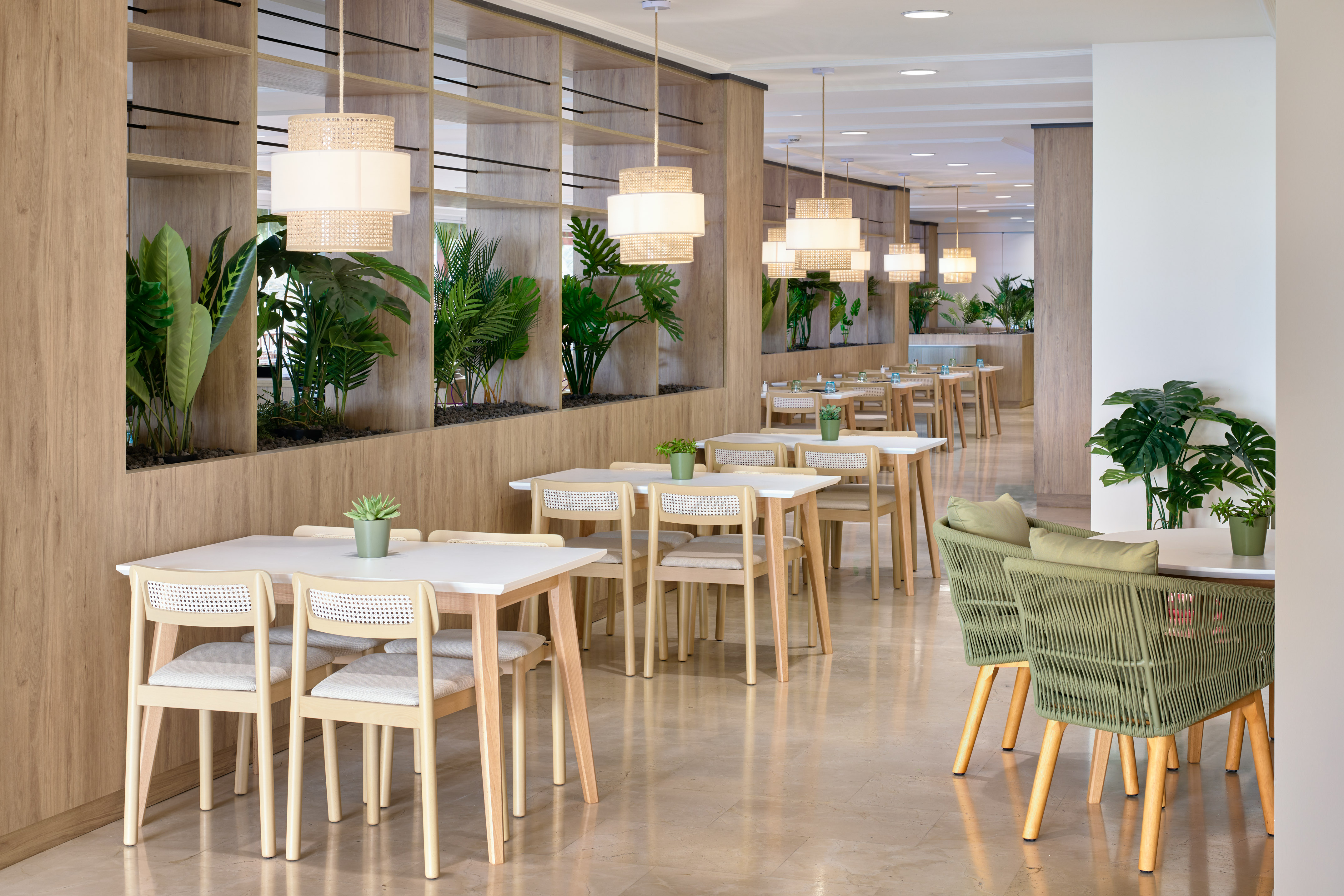 Bright, modern restaurant interior with wooden tables, cane chairs, and plants.