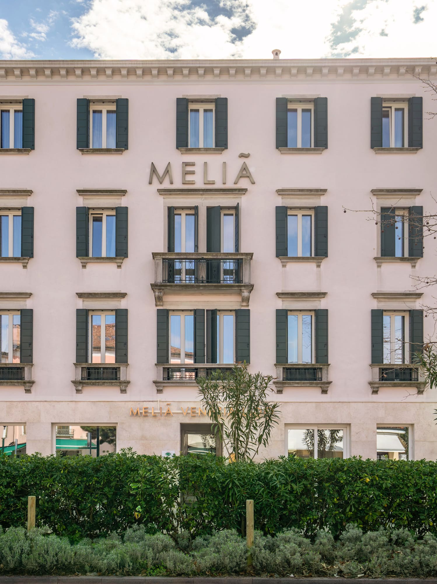 Meliá Venezia hotel exterior with green shutters and central balcony.