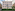 Melia hotel building with light facade, green shutters, balcony, and street-level hedge.