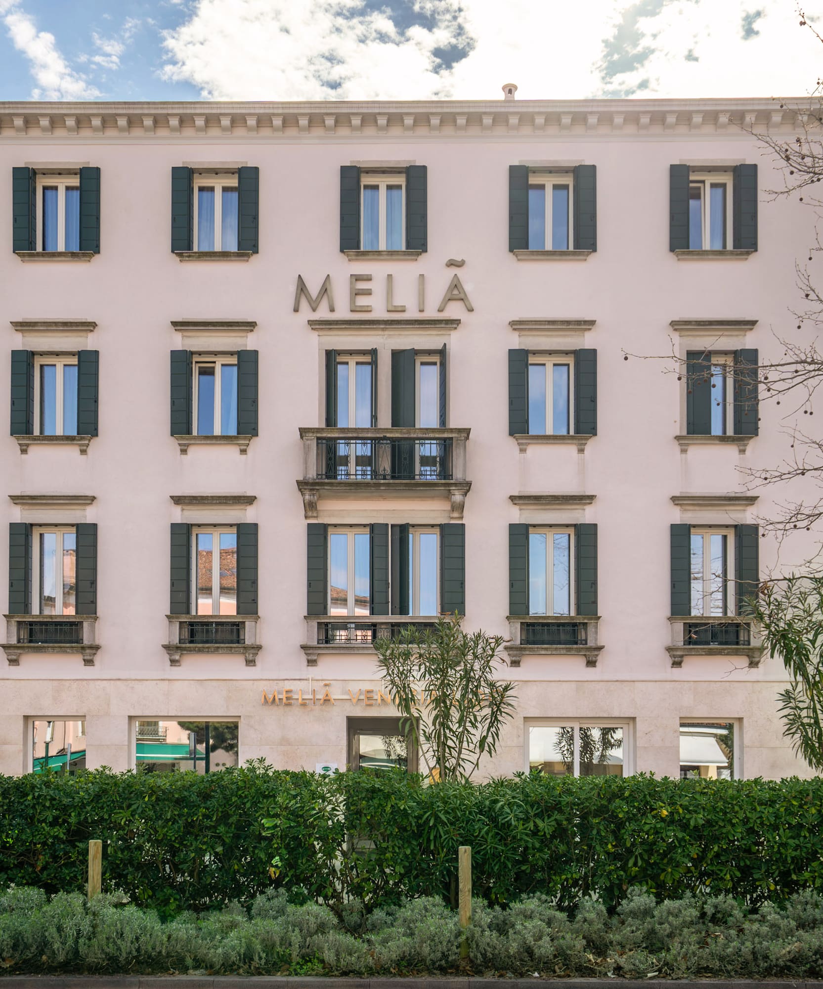 Meliá Venezia hotel exterior with green shutters and central balcony.