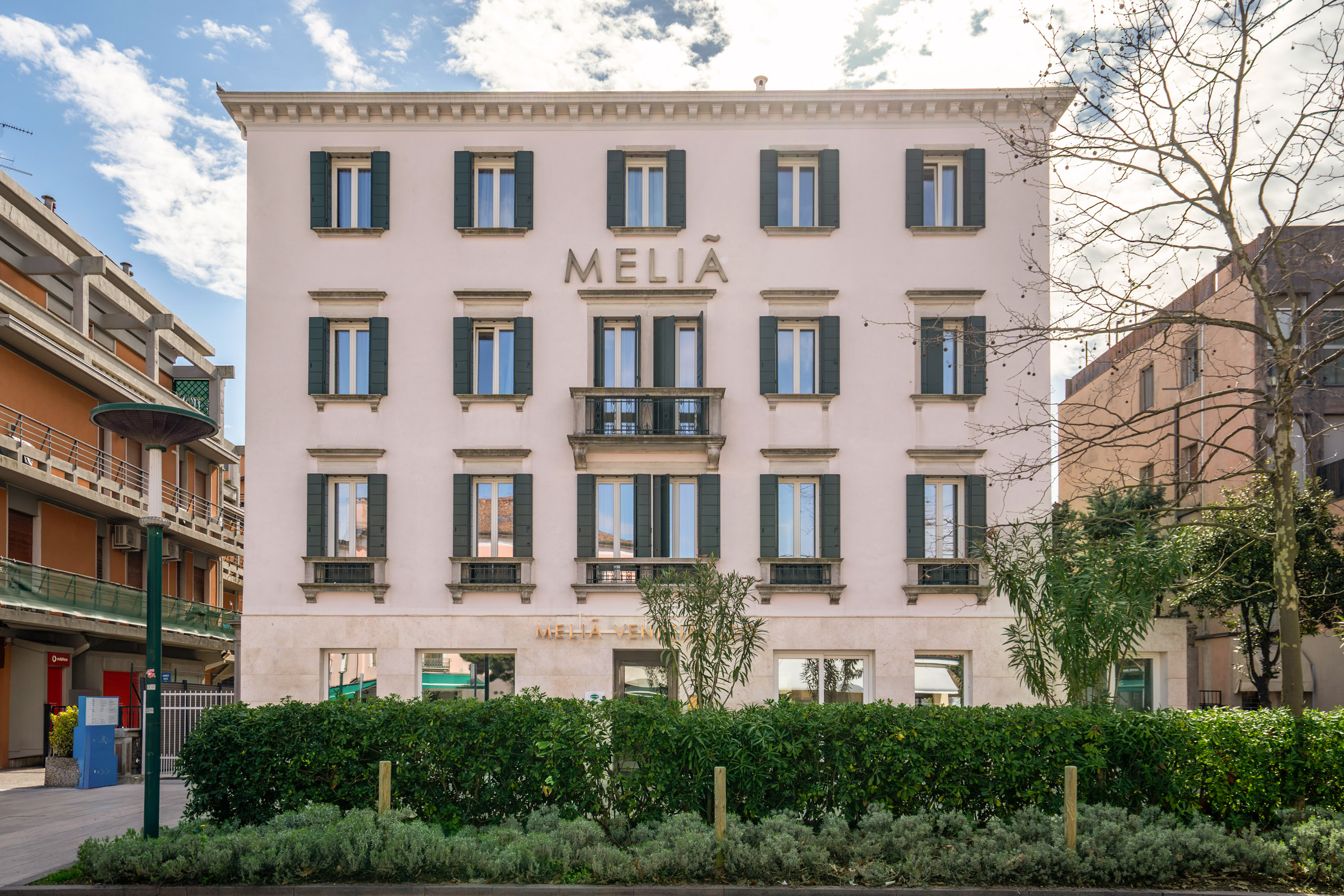 Meliá Venezia hotel exterior with green shutters and central balcony.