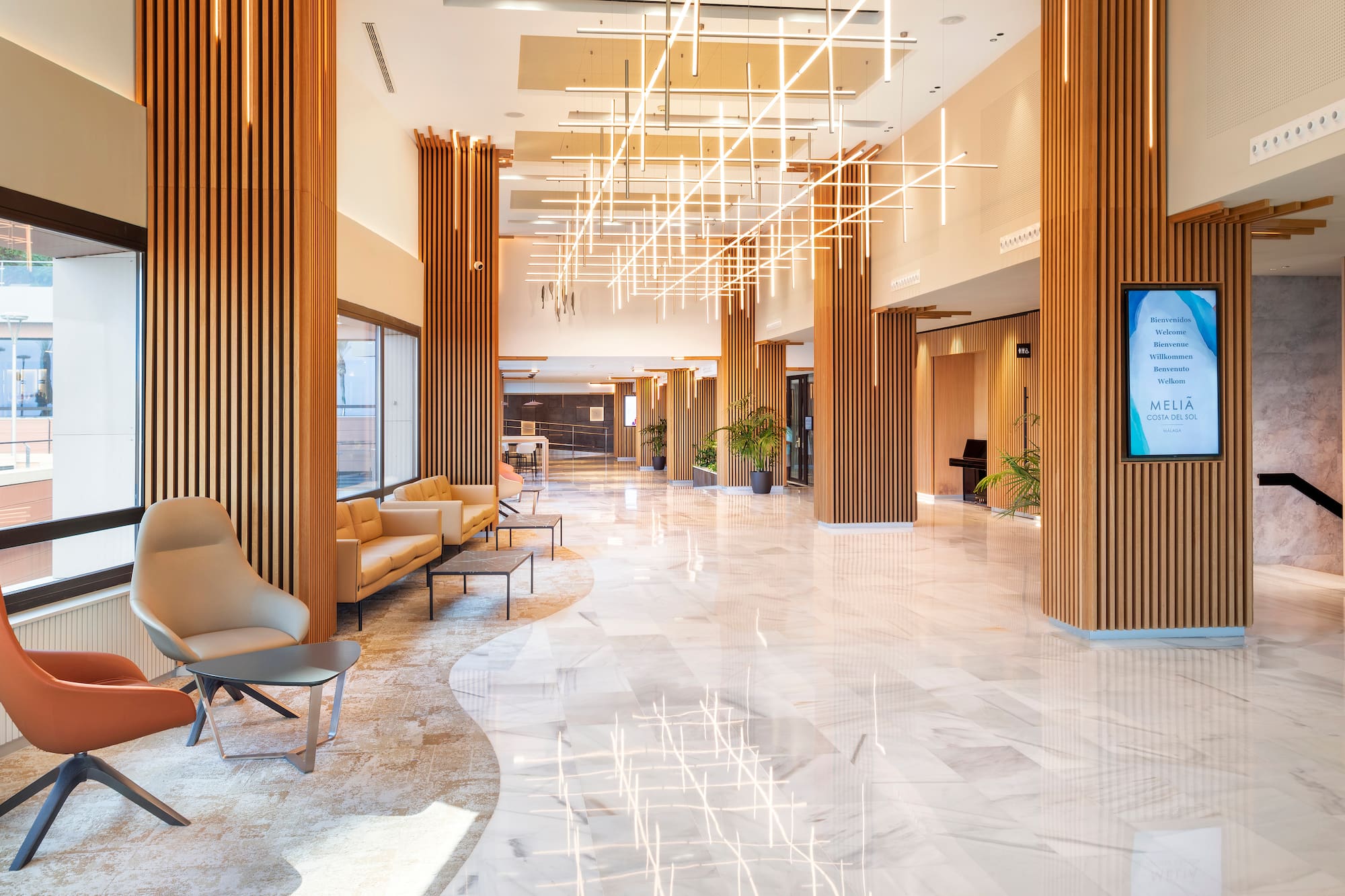 Meliá hotel reception with modern wood, marble floor, and lounge area.
