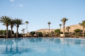 a pool with palm trees and mountains in the background