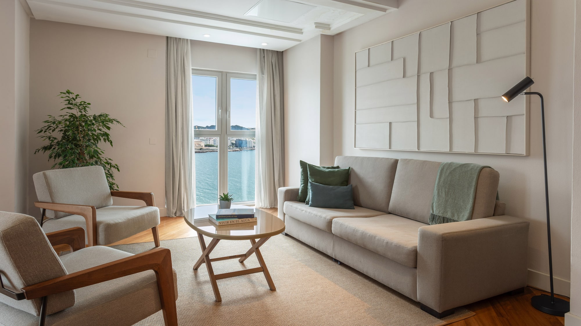 Salón moderno de apartamento con sofá, sillones y vistas al mar.