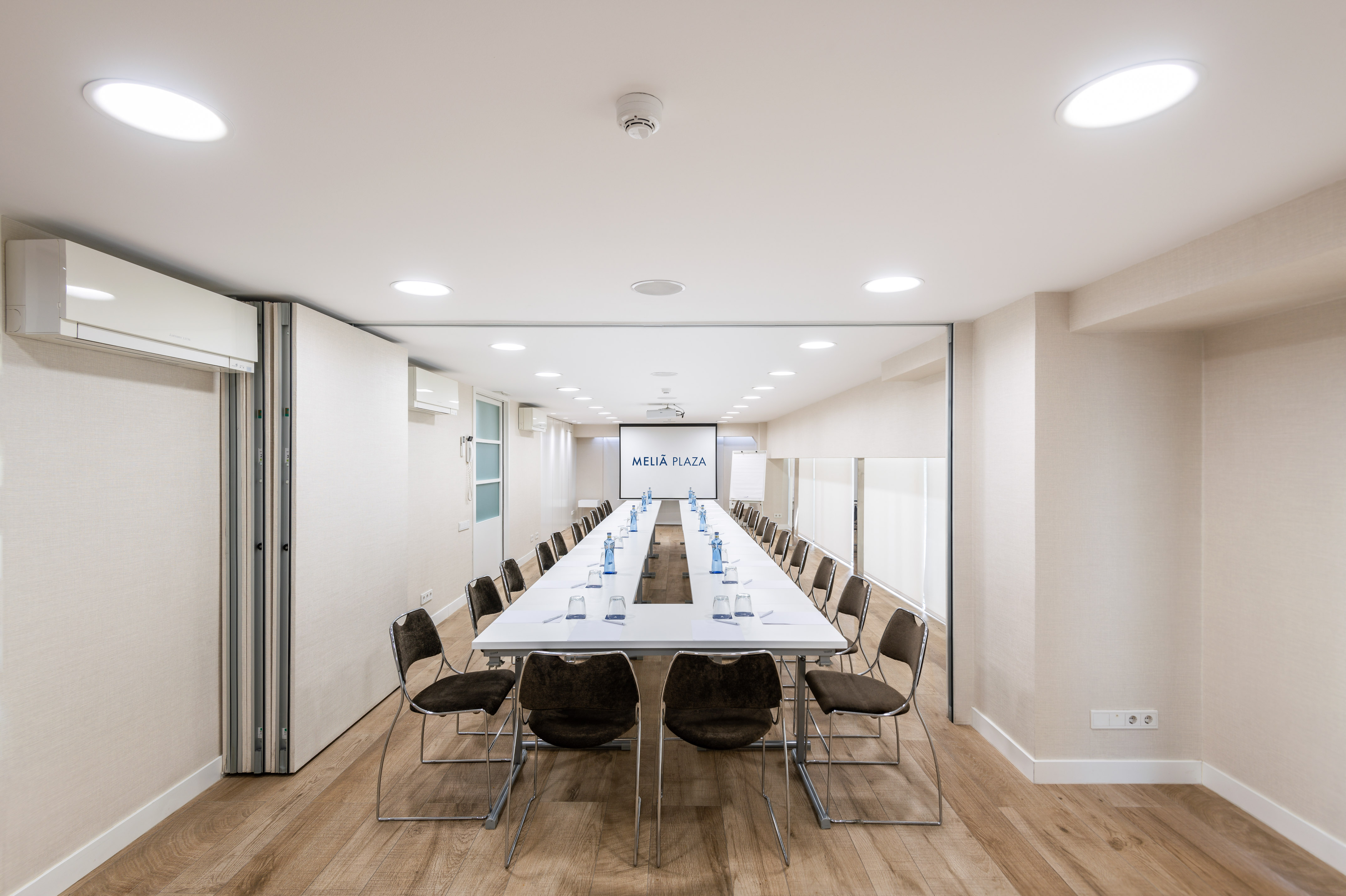 Modern Meliá Plaza conference room with large table and projector.