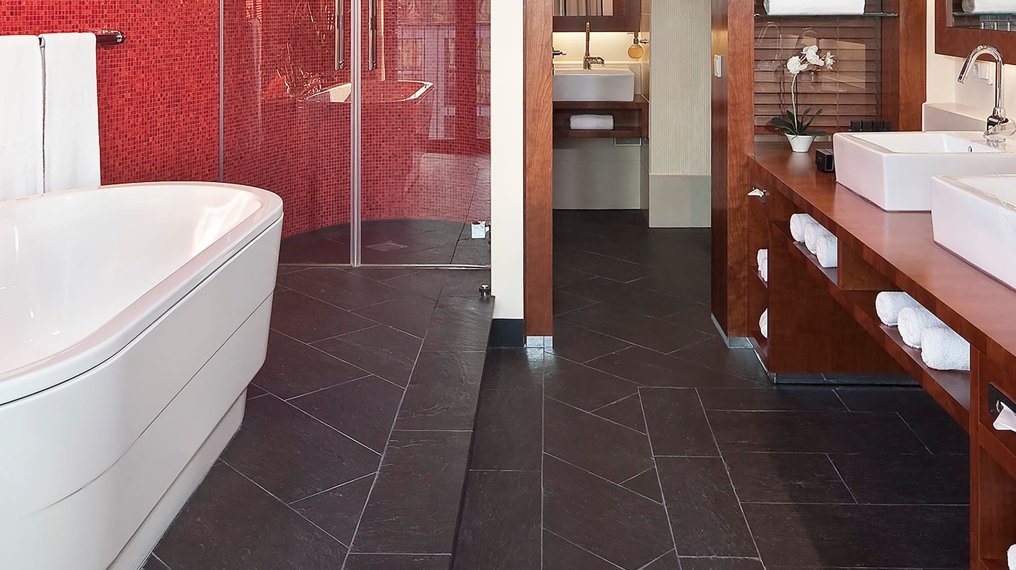 a bathroom with a red wall and a tub