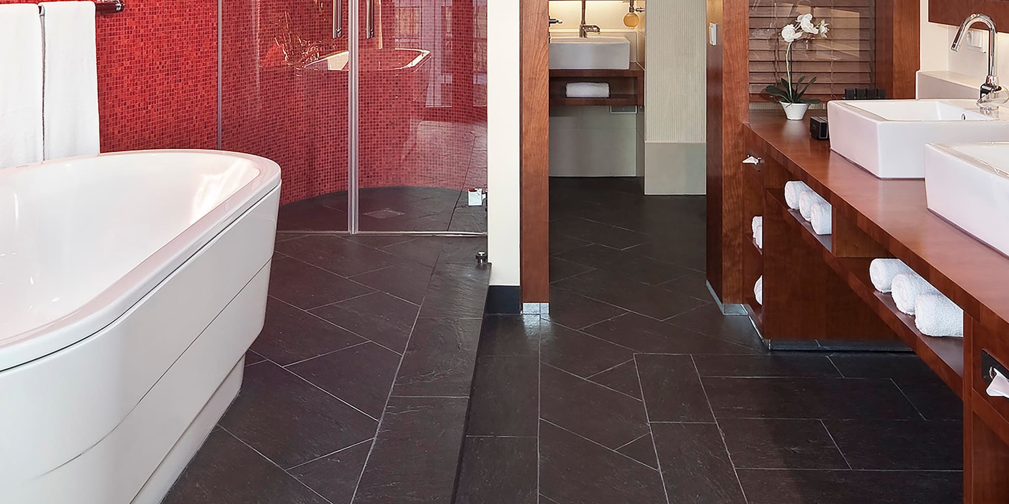 a bathroom with a red wall and a tub